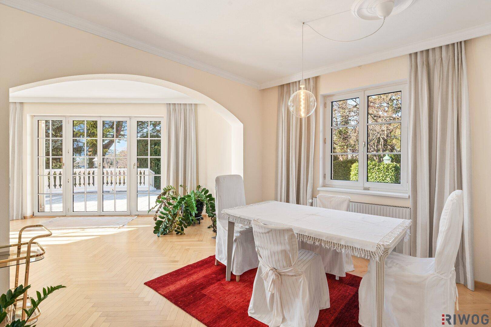 Heller Essbereich mit Fischgrätparkett, elegantem Esstisch und Zugang zur Terrasse.