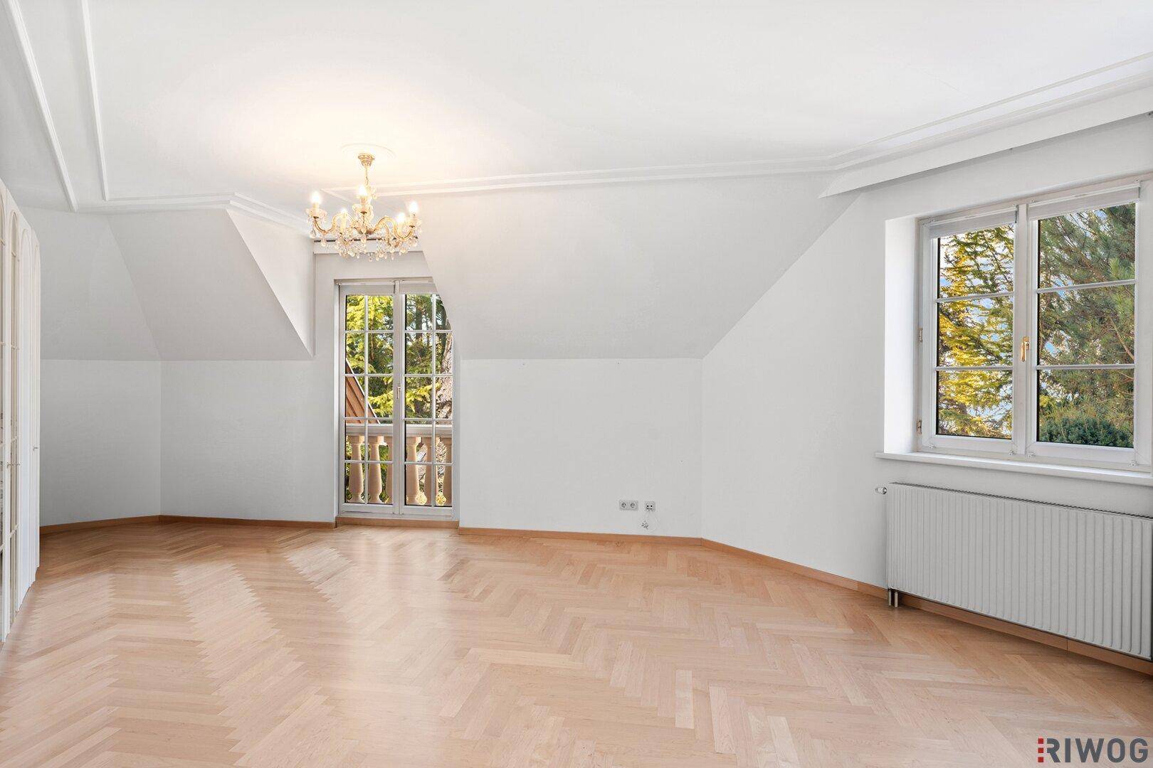 Geräumiger Raum mit Fischgrätparkett, Dachschrägen und Zugang zu einem französischen Balkon.