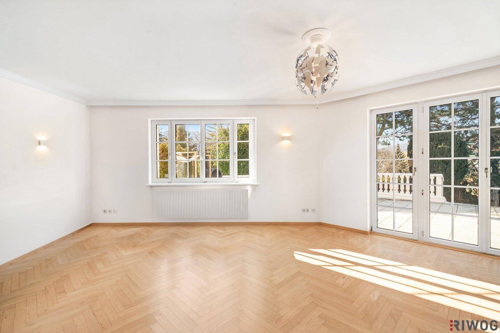 Geräumiges, lichtdurchflutetes Wohnzimmer mit klassischem Fischgrätparkett und Terrassenzugang.