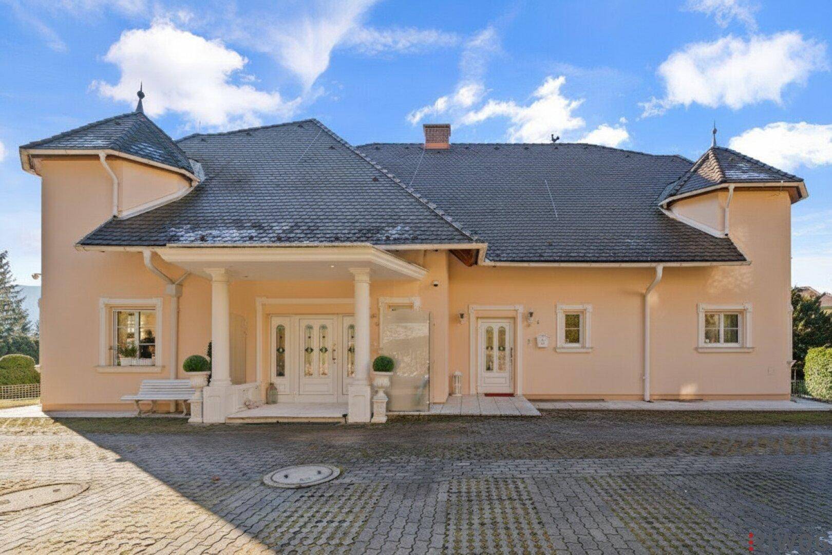 Elegante Fassade des Hauses mit repräsentativem Eingangsbereich und gepflasterter Auffahrt.