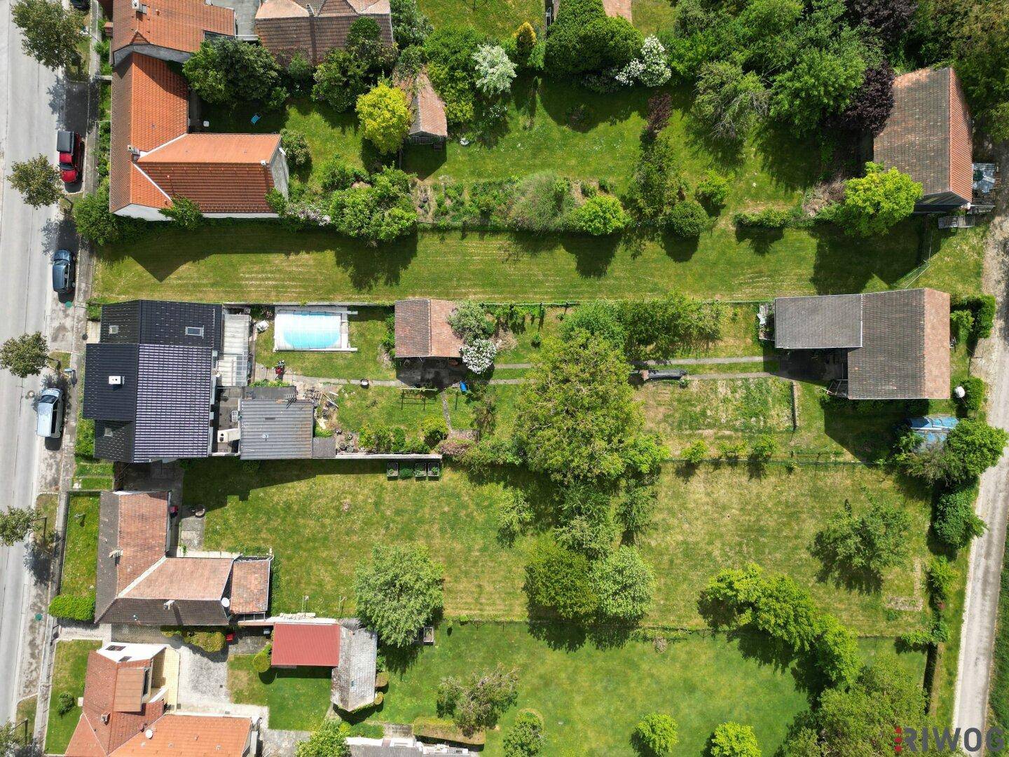Gesamtansicht des Grundstücks von oben mit Wohnhaus, langem Garten, Pool und mehreren Nebengebäuden.