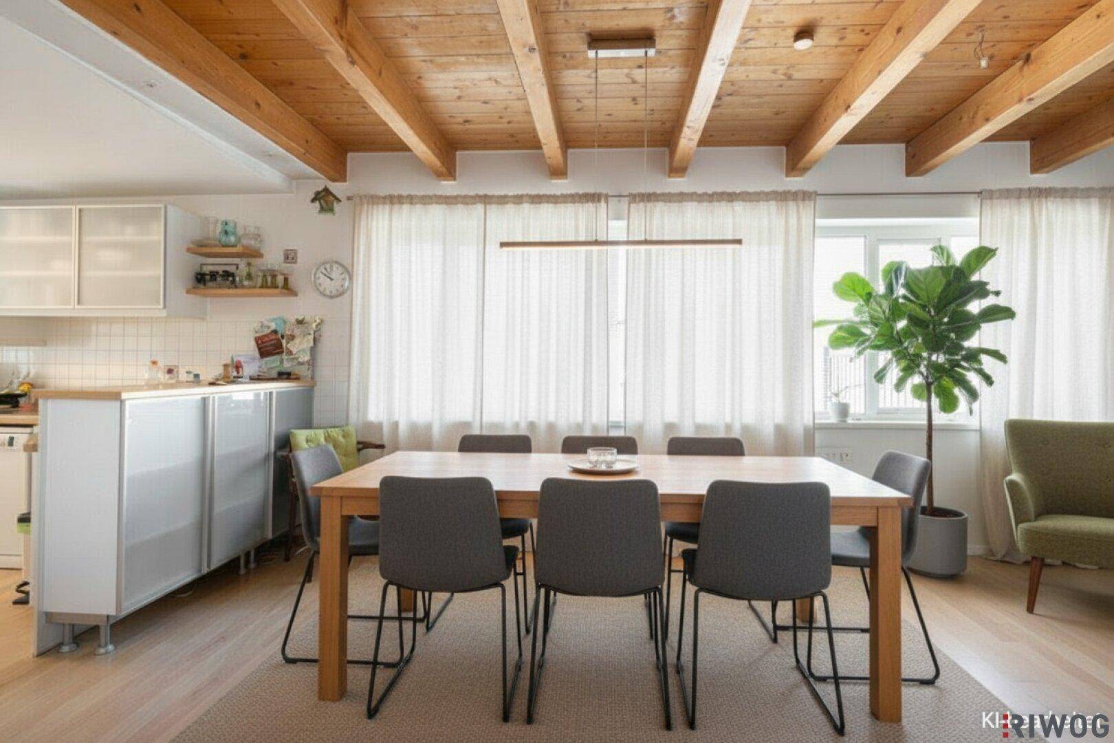 Modern inszenierter Essbereich mit Holztisch, bequemen Stühlen und sichtbaren Deckenbalken.