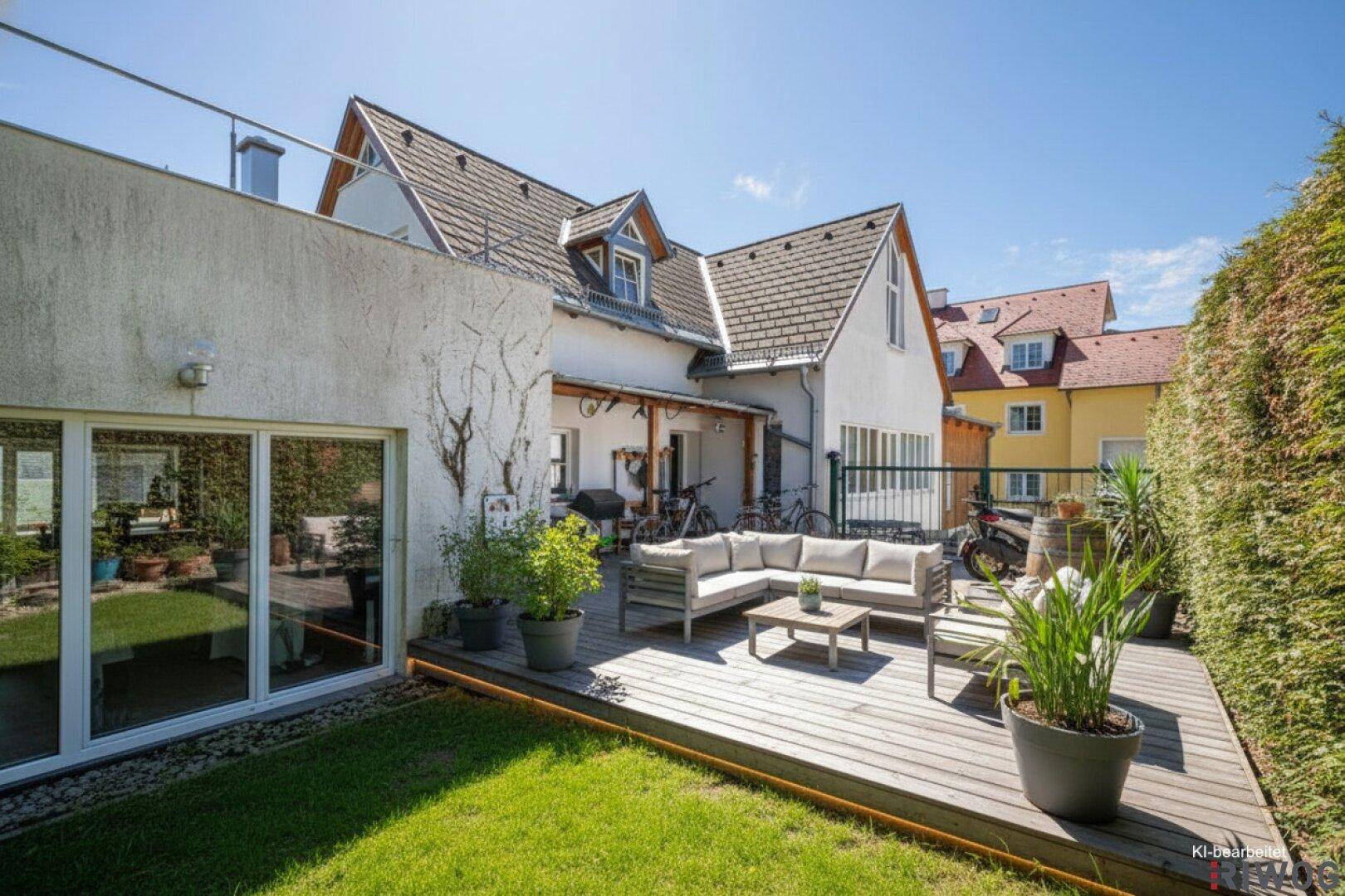 Große Holzterrasse mit modernen Gartenmöbeln und direktem Zugang zum Gartenbereich.
