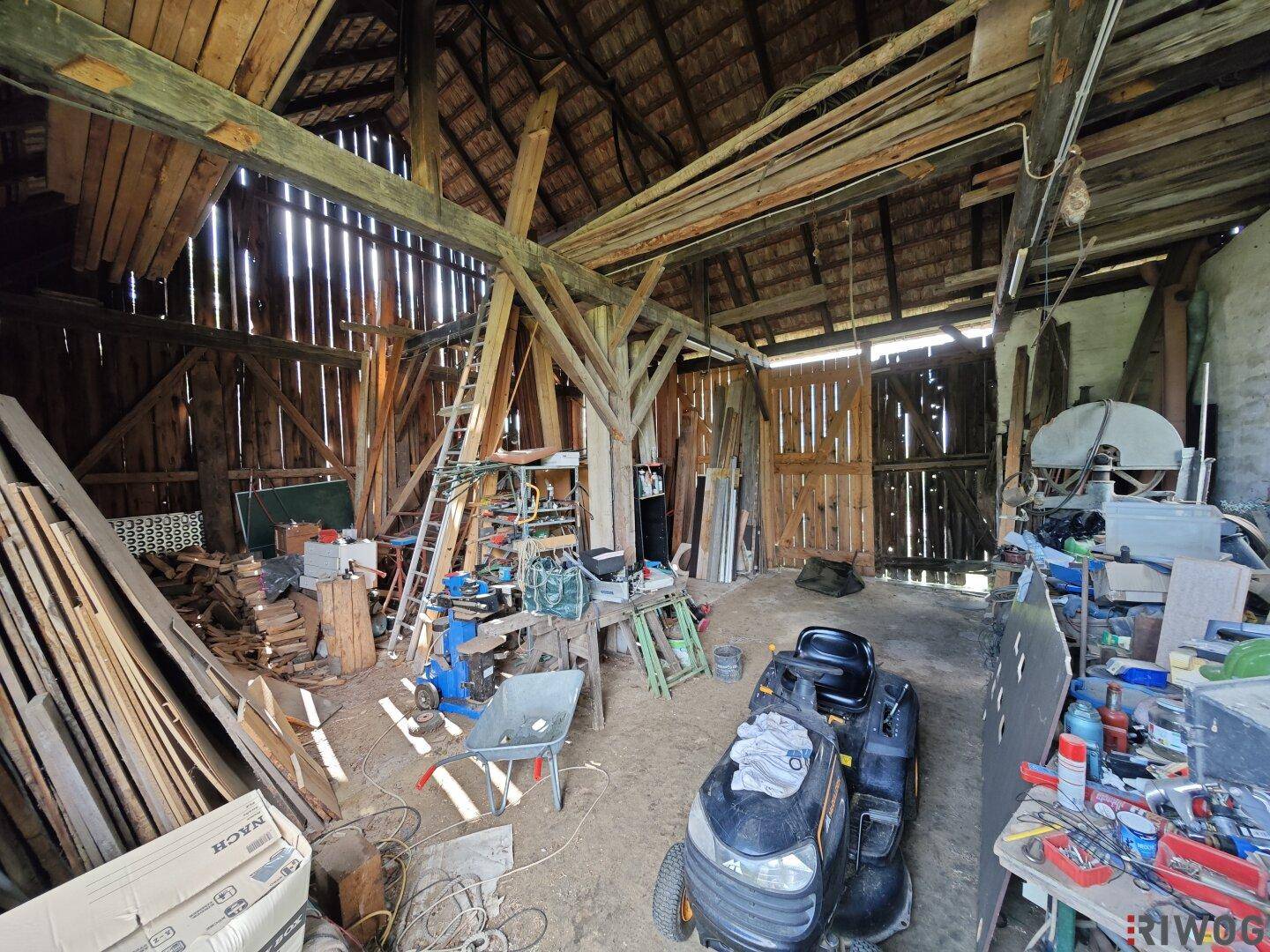 Rustikaler Innenraum einer Scheune mit sichtbaren Holzbalken und viel Stauraum, ideal für landwirtschaftliche Nutzung.