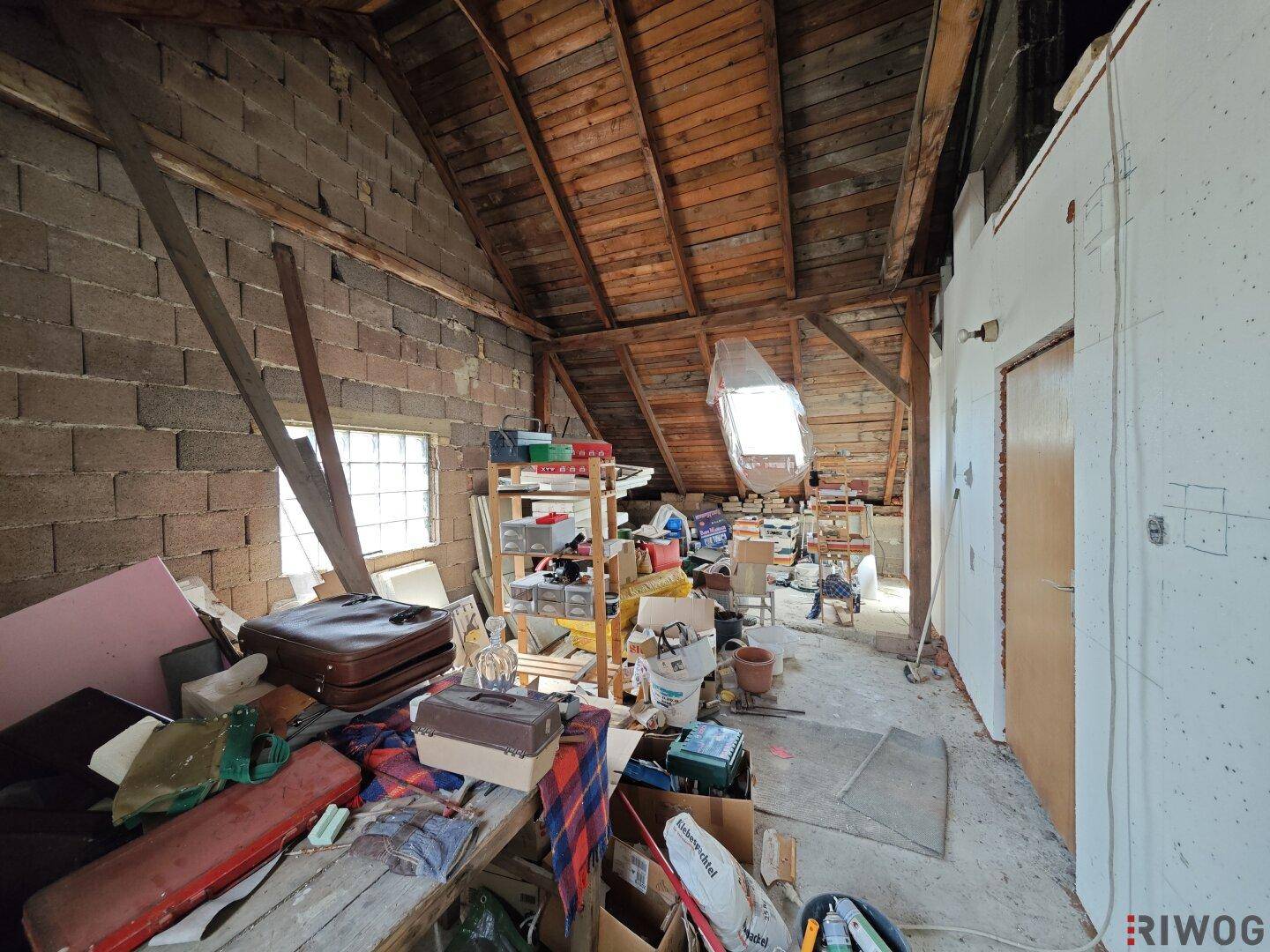 Unausgebauter Dachboden mit sichtbaren Holzbalken und Dachfenster, bietet viel Stauraum und Ausbaupotenzial.