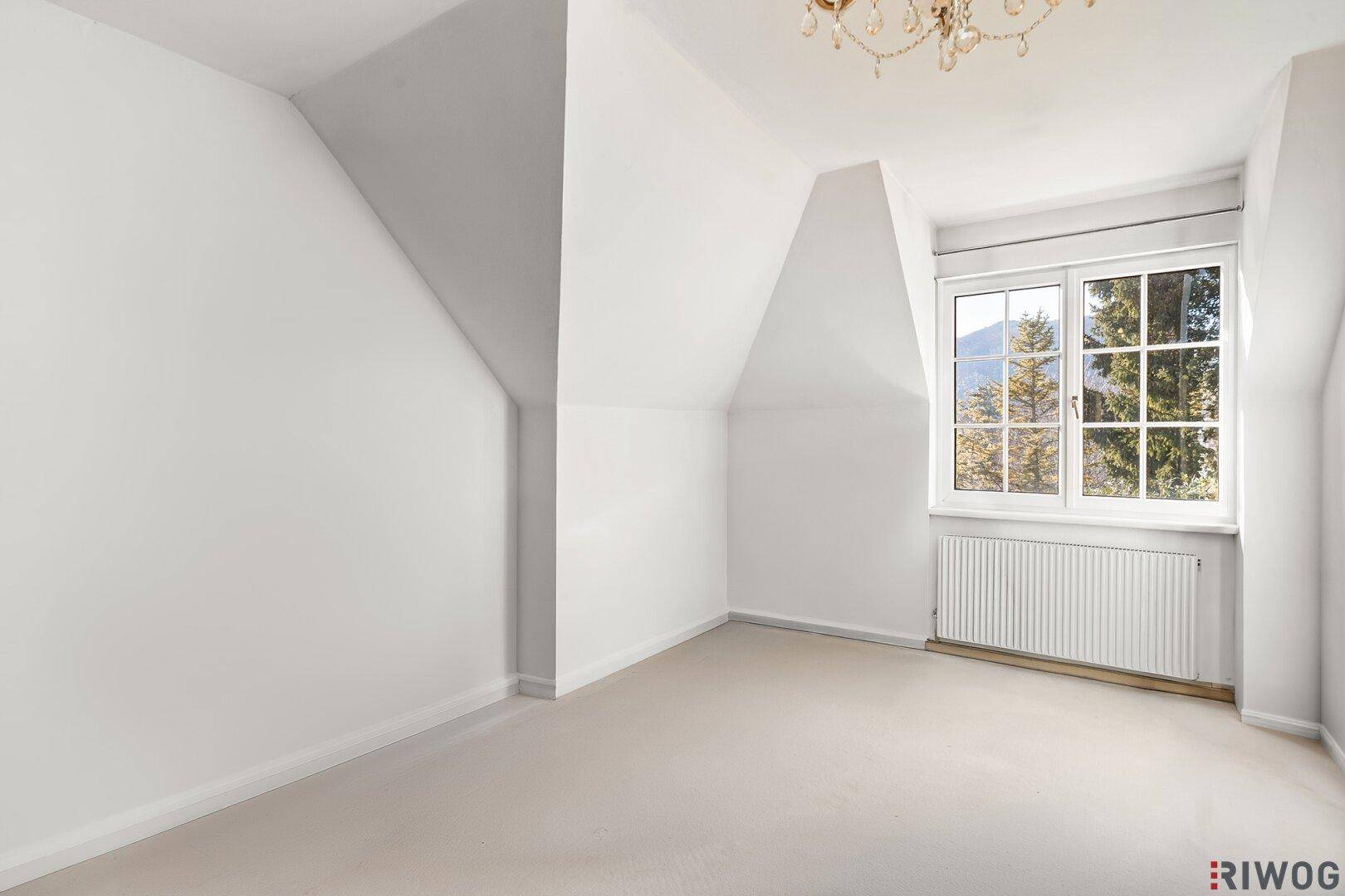 Helles Schlafzimmer im Dachgeschoss mit Teppichboden, Dachschrägen und Bergblick.