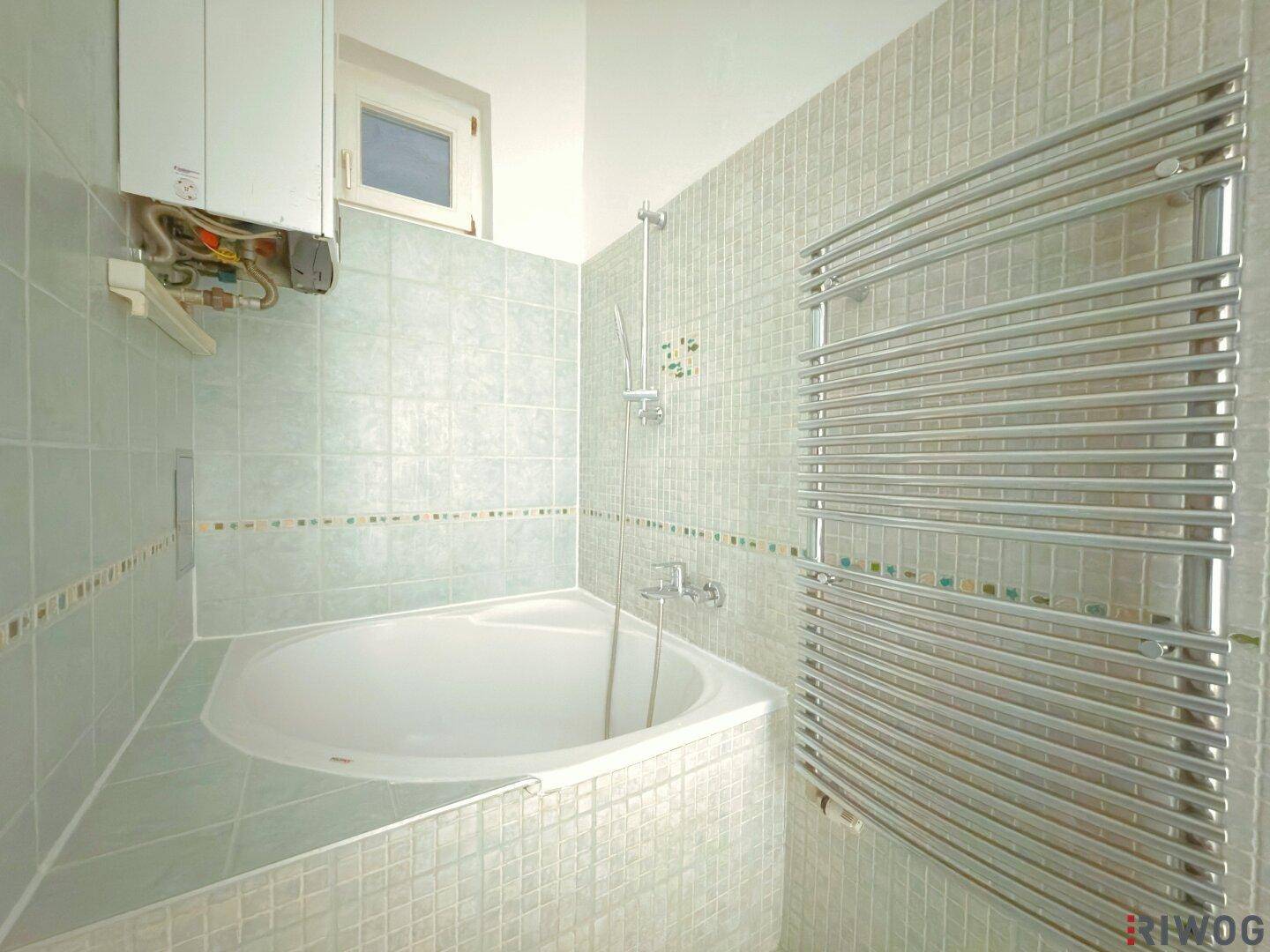 Modernes Badezimmer mit Eckbadewanne, hellblauen Fliesen und Handtuchheizkörper für Komfort.