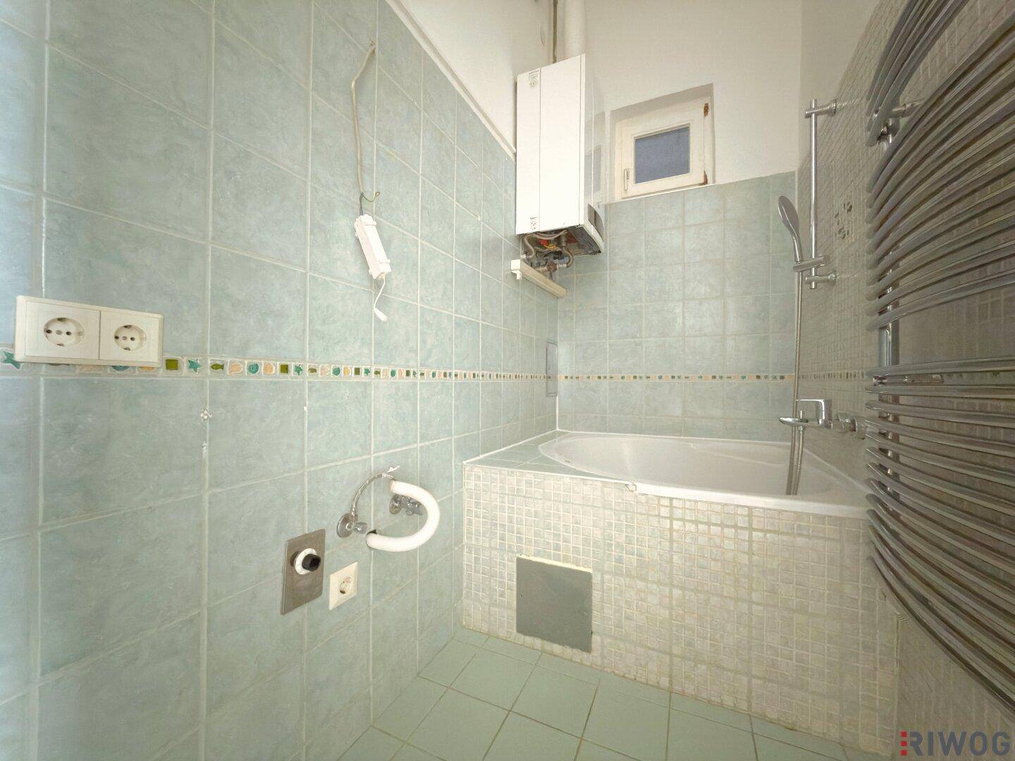 Funktionales Badezimmer mit Eckbadewanne, hellblauen Wandfliesen und Heizkörper.