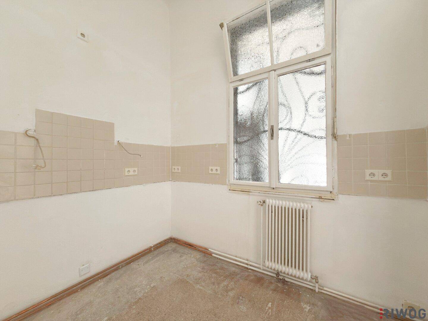 Geräumige Küche mit Fenster und Fliesenrückwand, die viel Potenzial für eine Neugestaltung bietet.