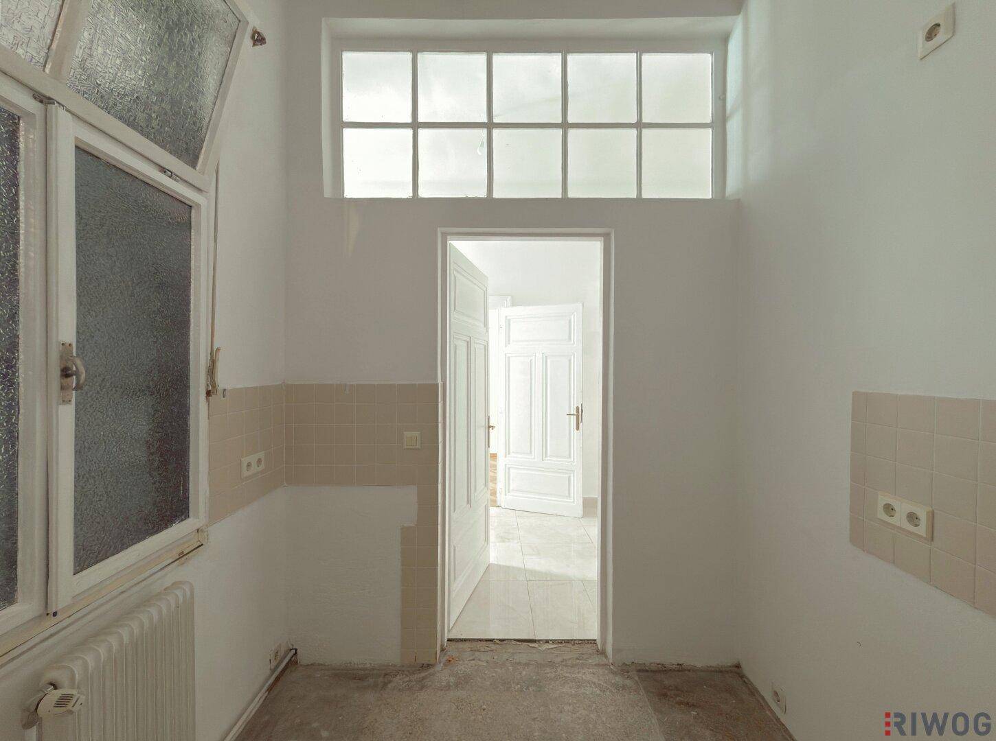 Leere Küche mit Fliesenrückwand und Fenster, bereit für den Einbau einer modernen Küchenzeile.