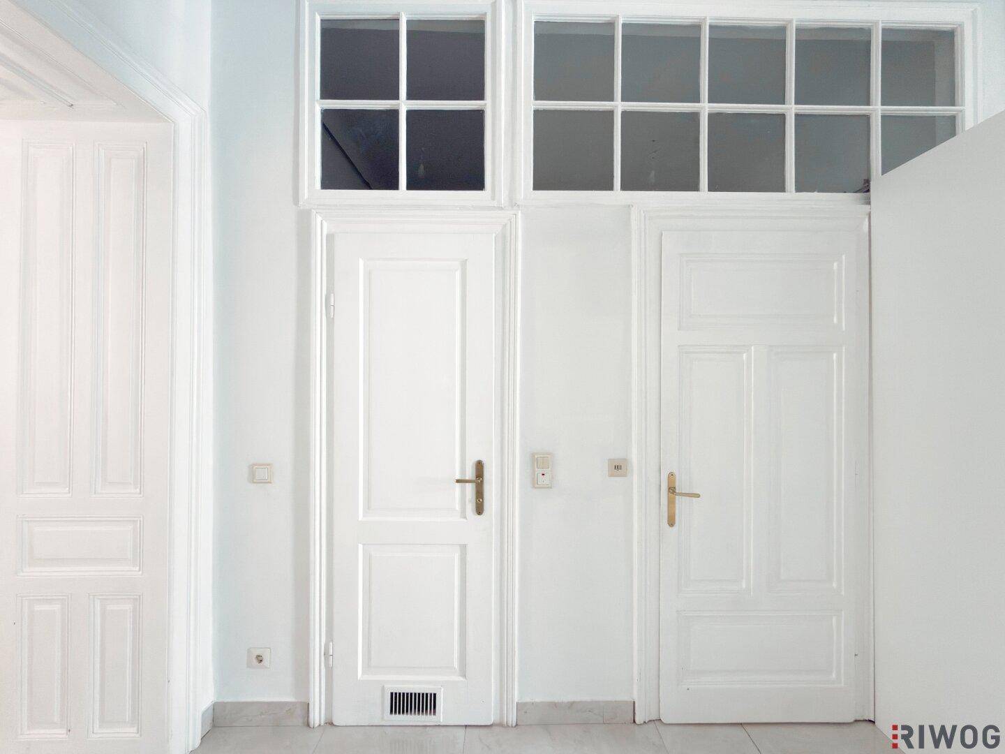 Heller Flur mit hohen Türen und Oberlichtern, der eine klassische Altbau-Atmosphäre vermittelt.
