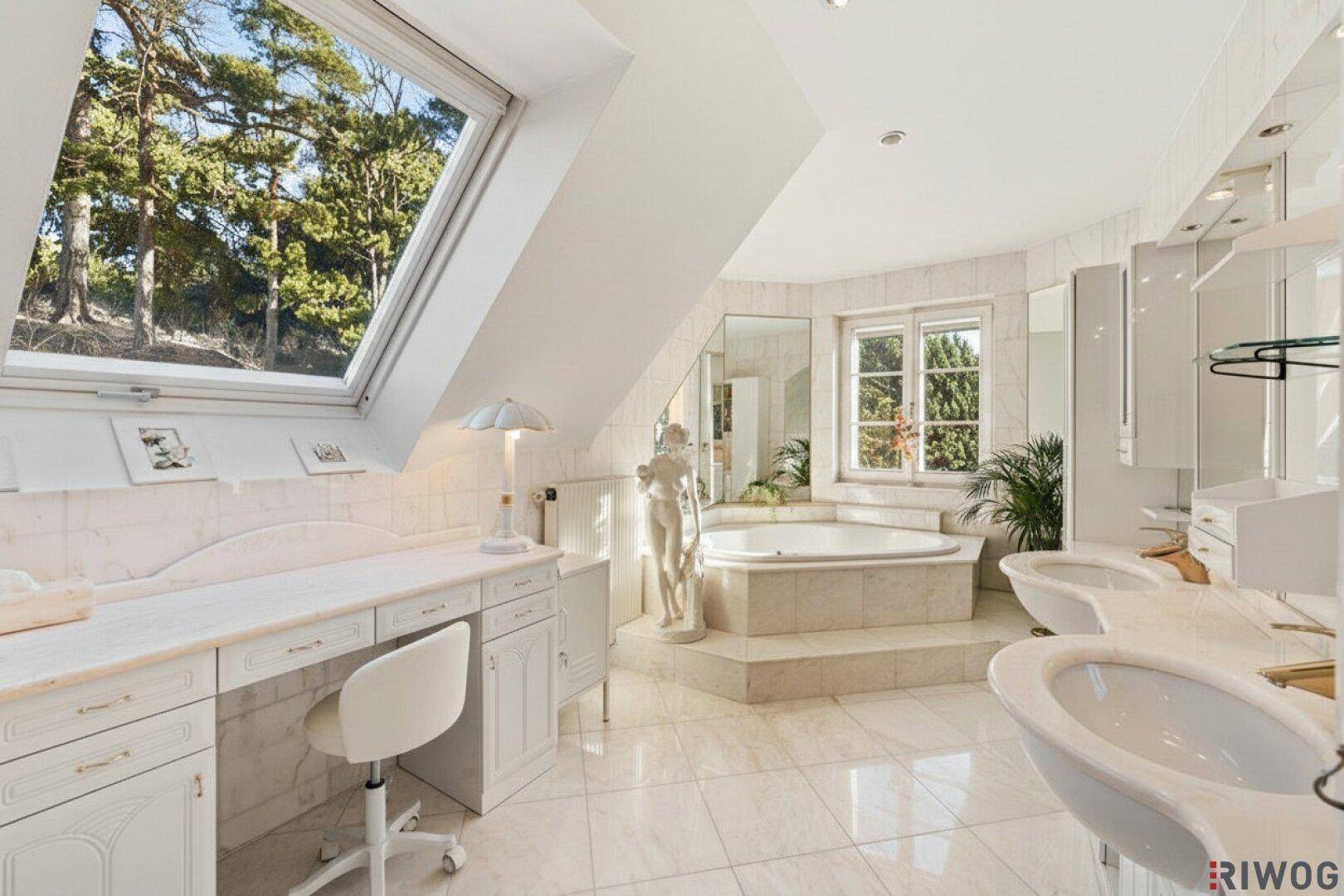 Luxuriöses Badezimmer mit Badewanne, Doppelwaschbecken, Marmorfliesen und Dachfenster.