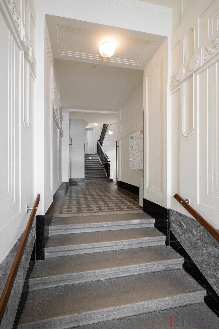 Repräsentativer Eingangsbereich mit Marmorverkleidung, Schachbrettmuster-Fliesen und breiter Treppe.