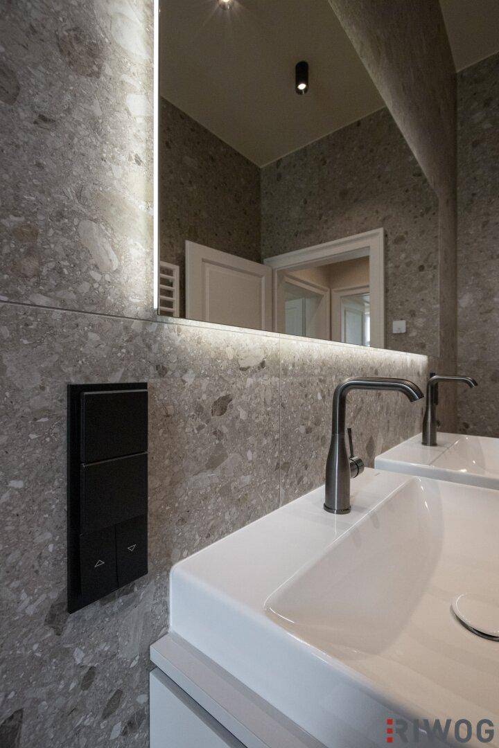 Detailaufnahme des beleuchteten Spiegels und der modernen Armaturen im Badezimmer.