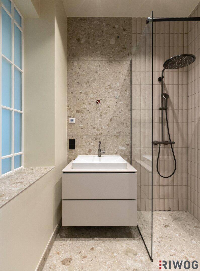 Elegantes Badezimmer mit moderner Ausstattung, begehbarer Dusche und großformatigen Fliesen.