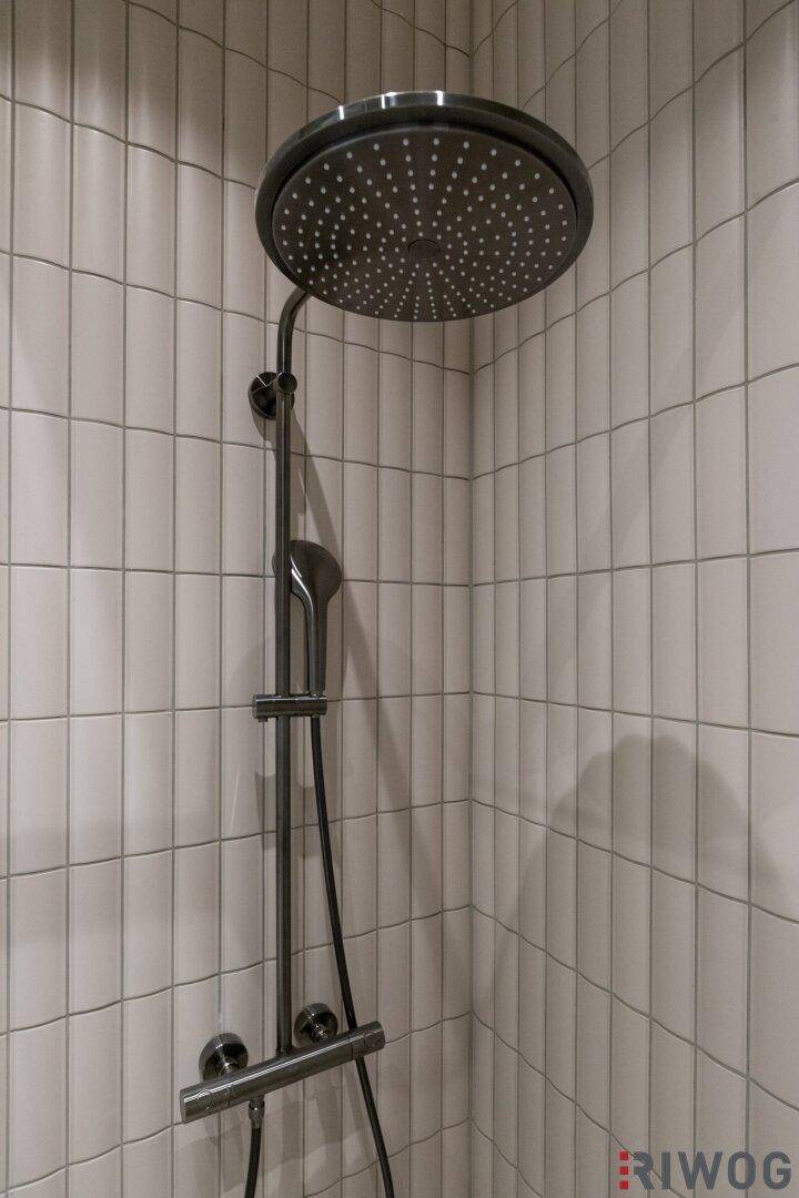 Detailaufnahme einer modernen Regendusche in einem stilvoll gefliesten Duschbereich.