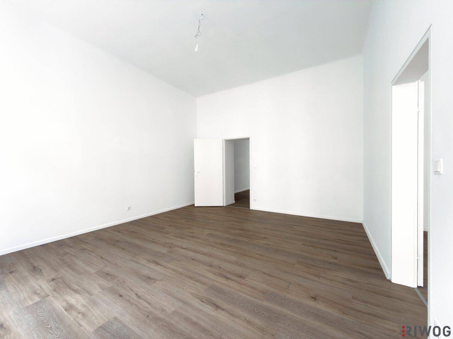 Leerer Raum mit dunklem Holzboden und weiß gestrichenen Wänden, bereit für Möbel.