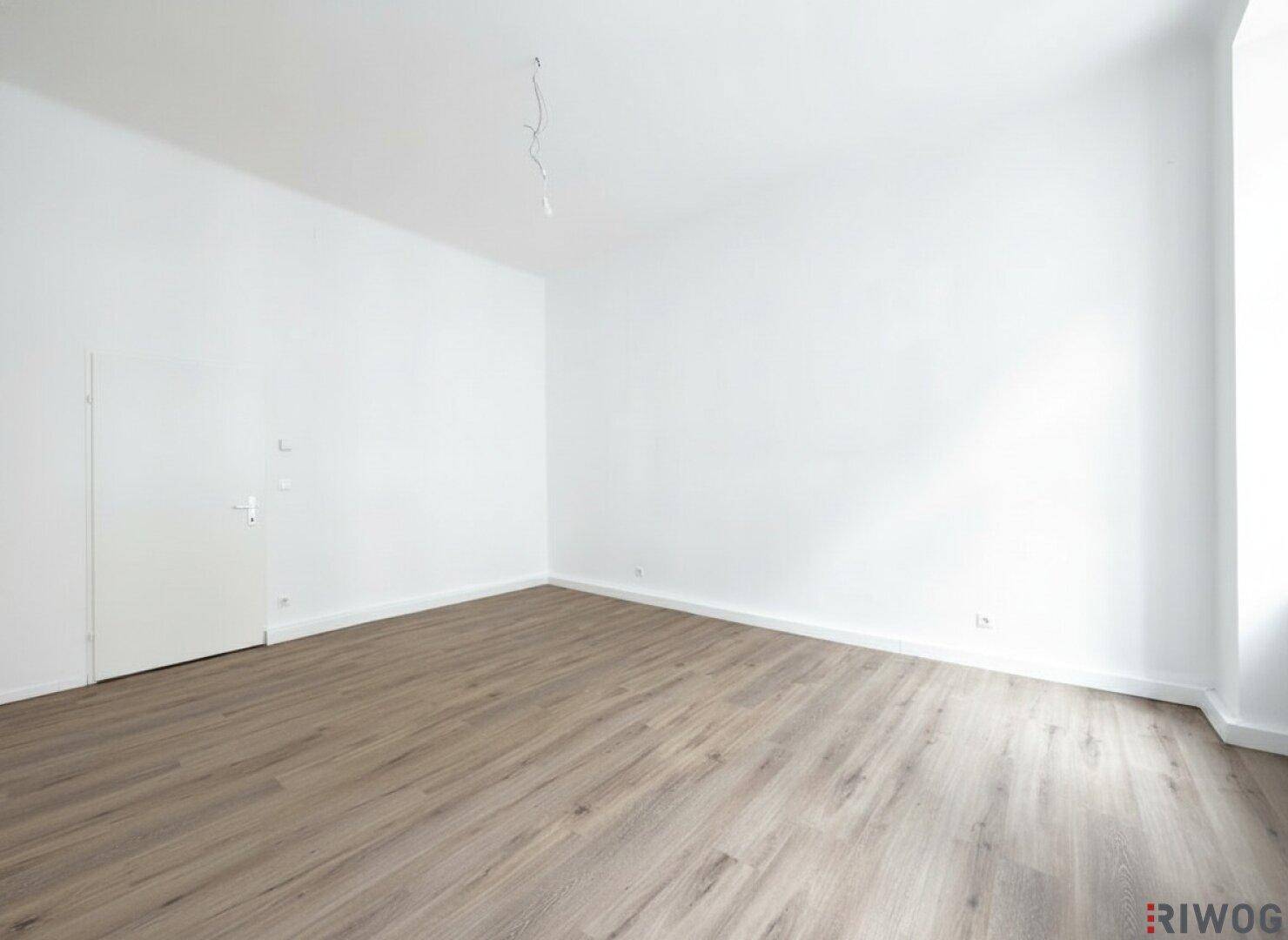 Leerer Raum mit Holzboden und weiß gestrichenen Wänden, ideal für individuelle Einrichtung.