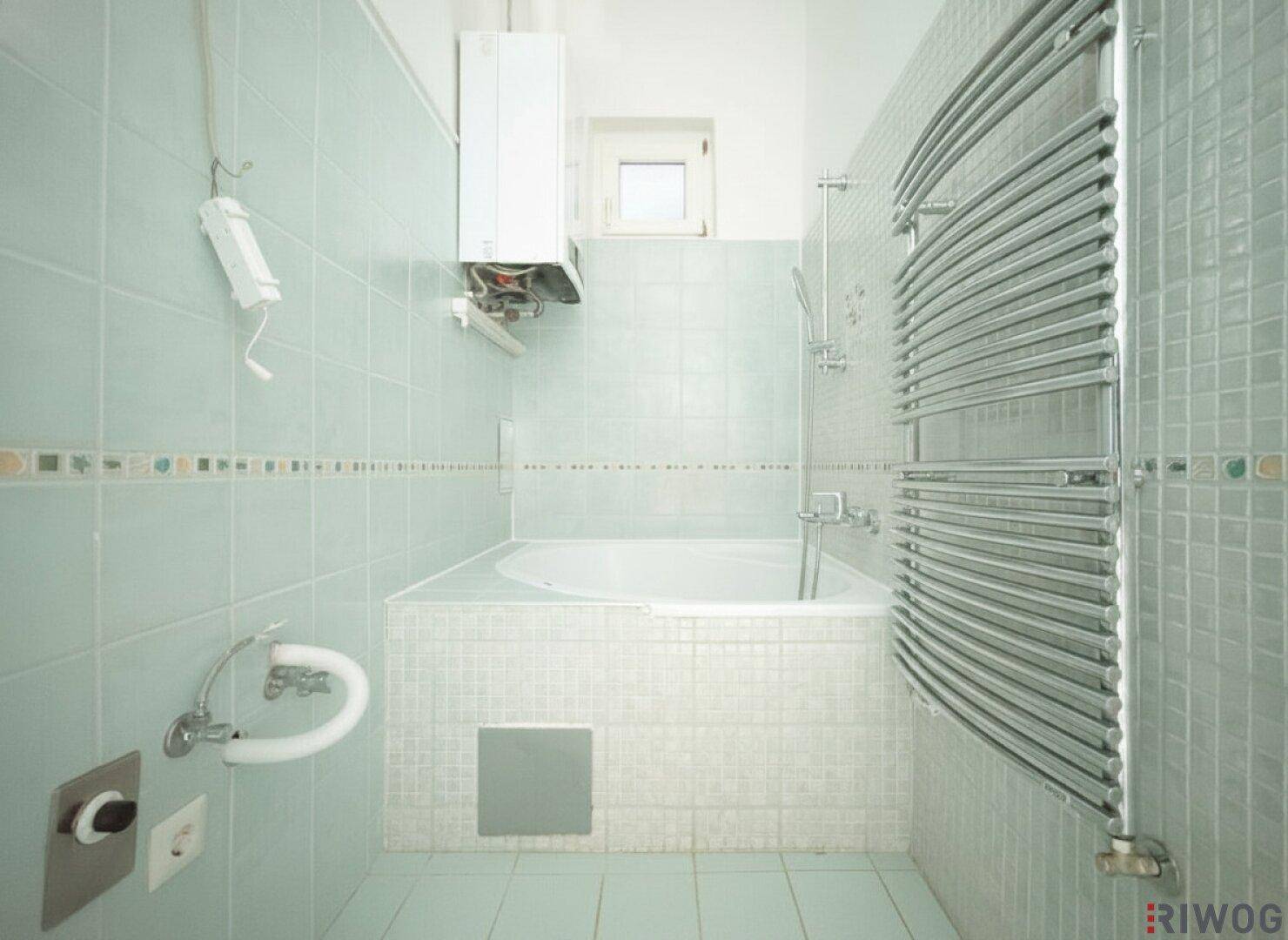 Badezimmer mit Eckbadewanne, hellblauen Fliesen und einem praktischen Handtuchheizkörper.