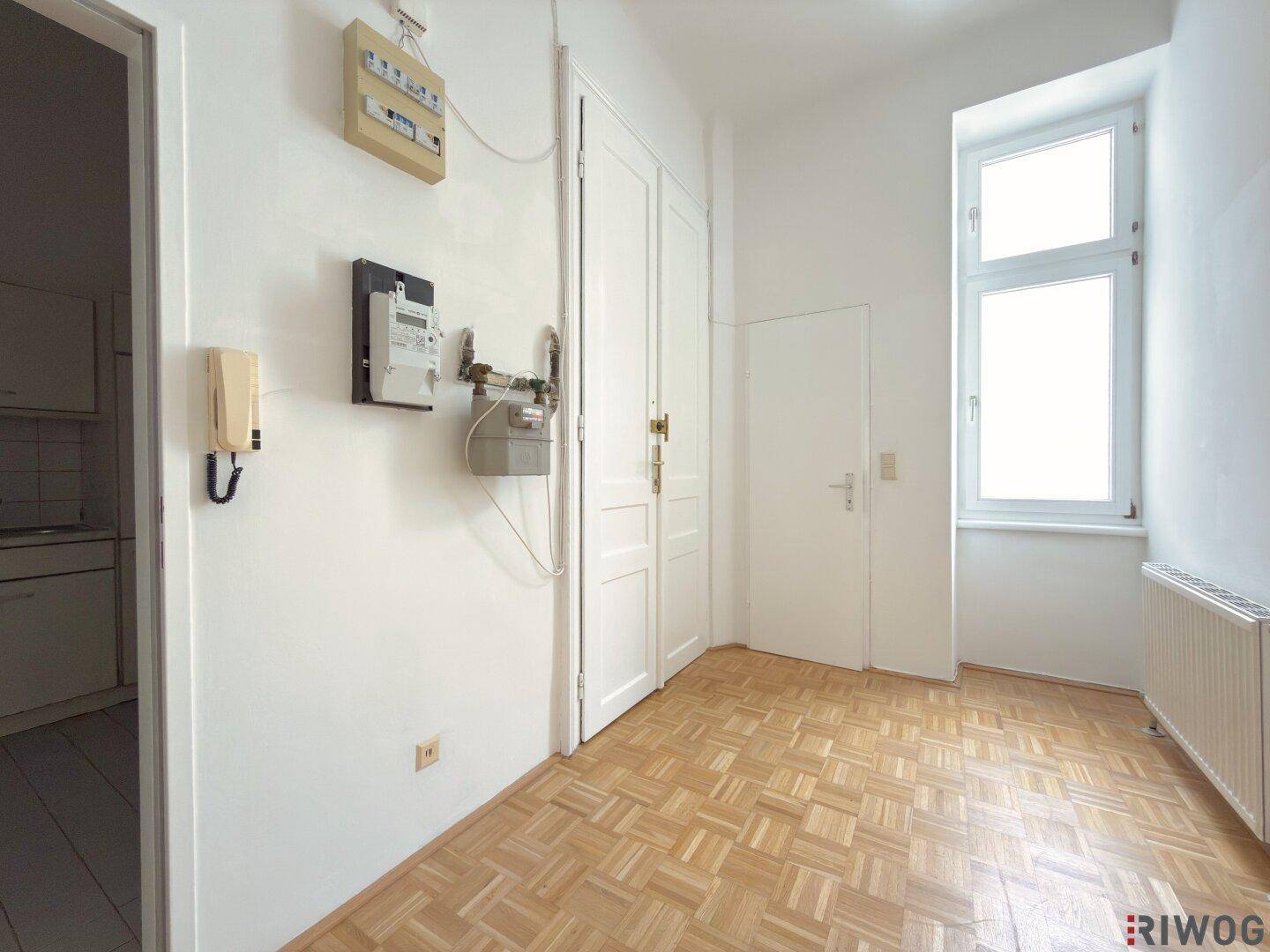 Heller Flur mit Parkettboden, mehreren Türen und einem Fenster.