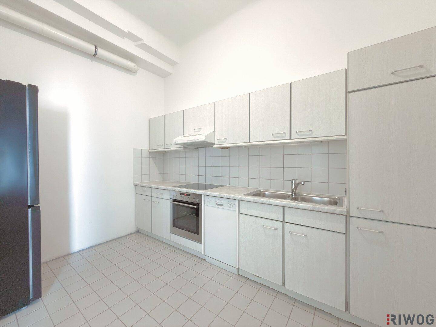 Küche mit Einbauküche, Fliesenboden und einem freistehenden Kühlschrank.