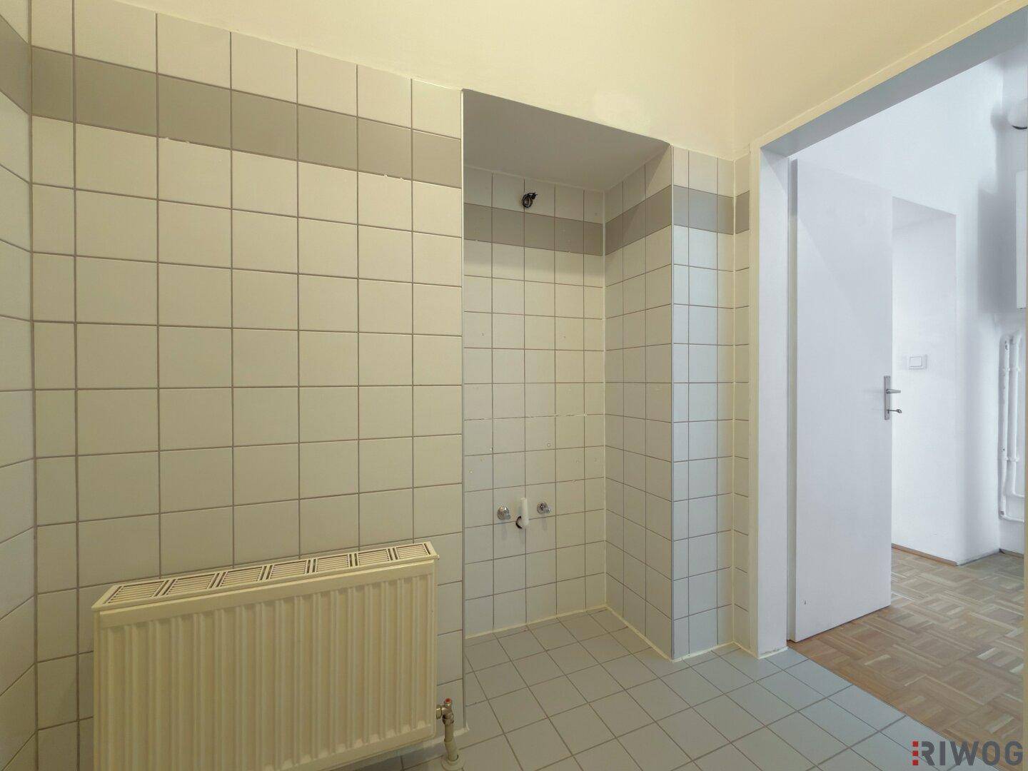 Gefliestes Badezimmer mit Heizkörper und Anschlüssen für weitere Sanitärobjekte.