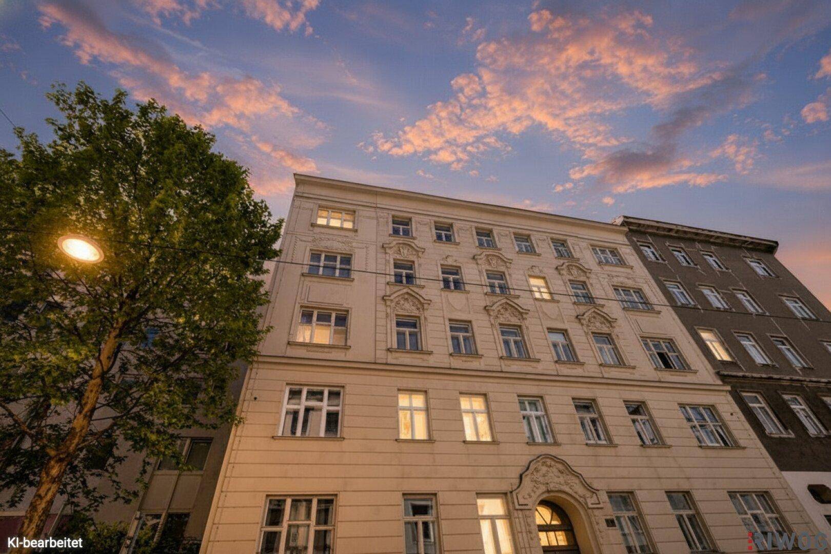 Gut erhaltene Fassade eines Mehrfamilienhauses mit klassischen Zierelementen unter einem dramatischen Abendhimmel.