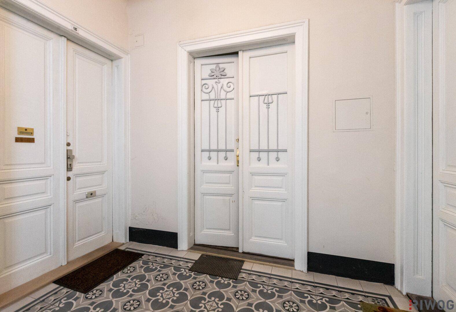 Geräumiger Eingangsbereich mit zwei verzierten Türen und einem eleganten Fliesenboden.
