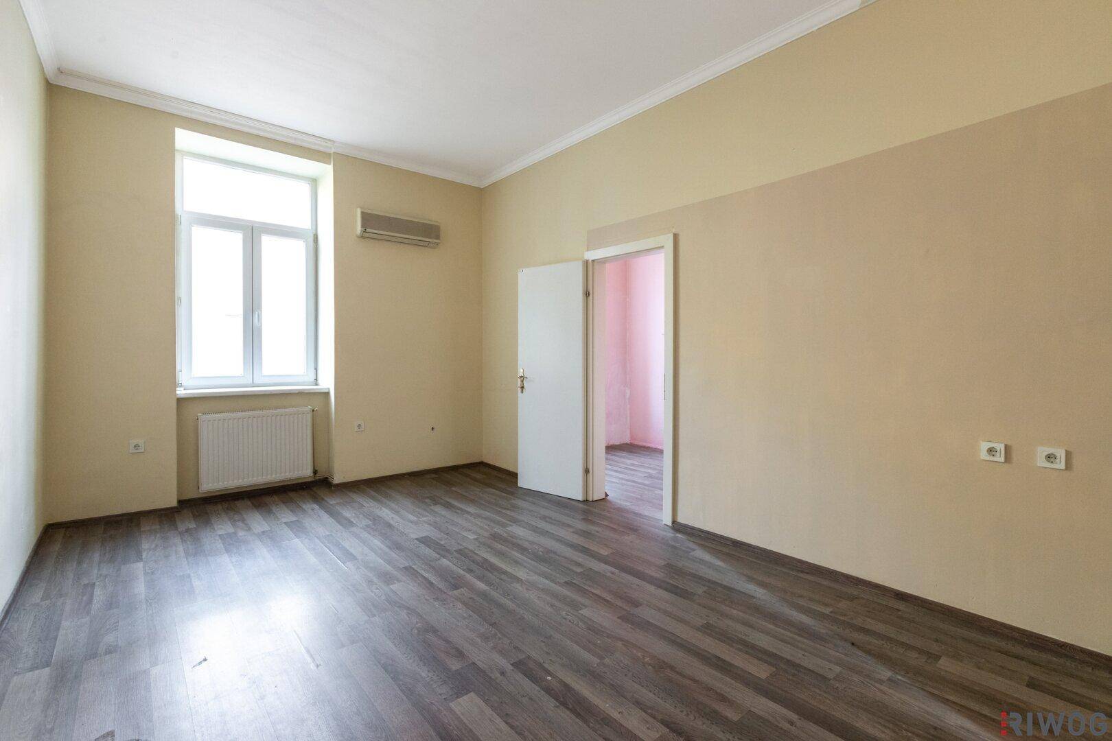 Unmöblierter Raum mit Laminatboden und beigen Wänden, bereit zur Renovierung und Gestaltung.