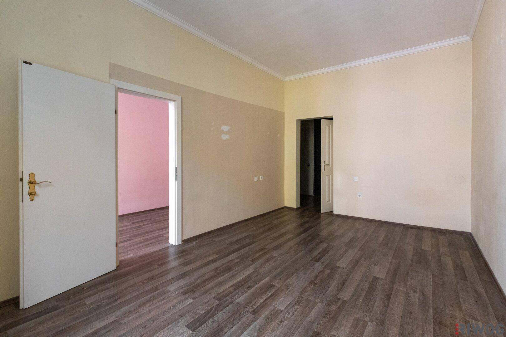 Leerer Raum mit Laminatboden und teilweise gestrichenen Wänden, ideal für individuelle Gestaltung.