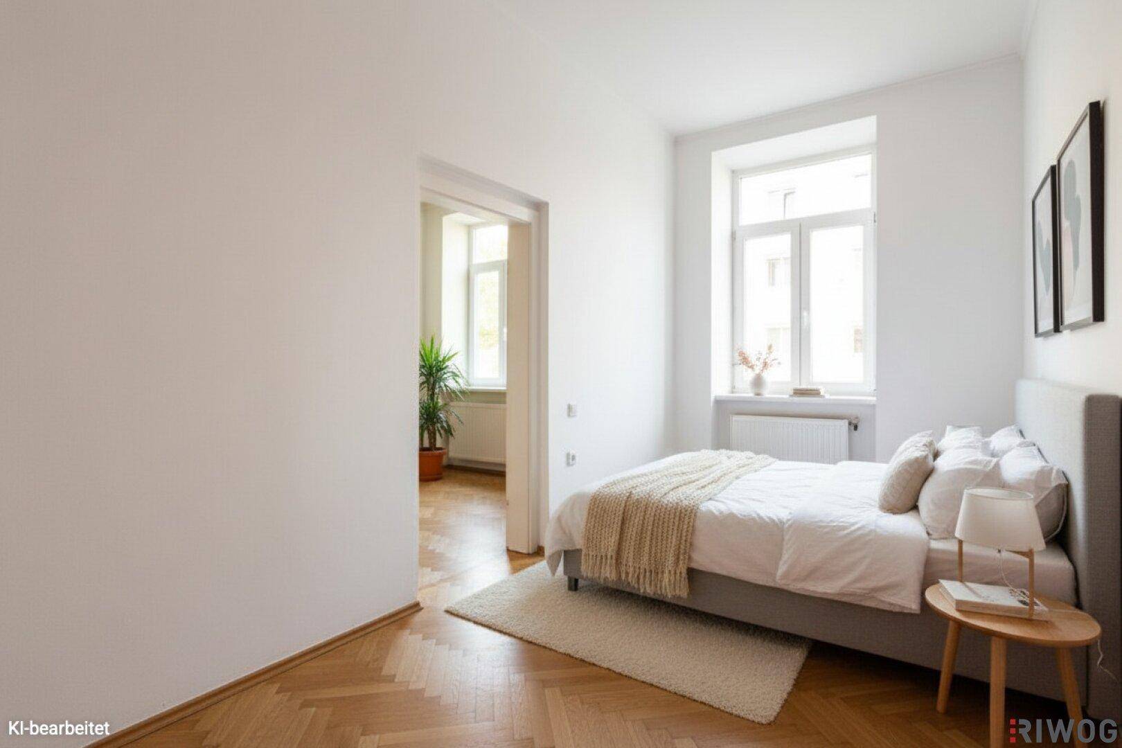 Helles Schlafzimmer mit Fischgrätparkett, Doppelbett und Fenster mit viel Tageslicht.