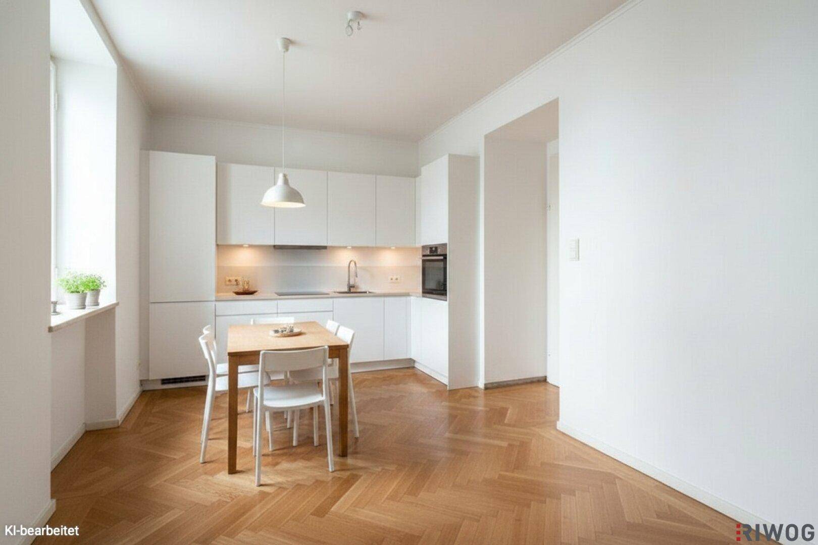 Moderne, helle Einbauküche mit weißer Front, Esstisch und Fischgrätparkett.