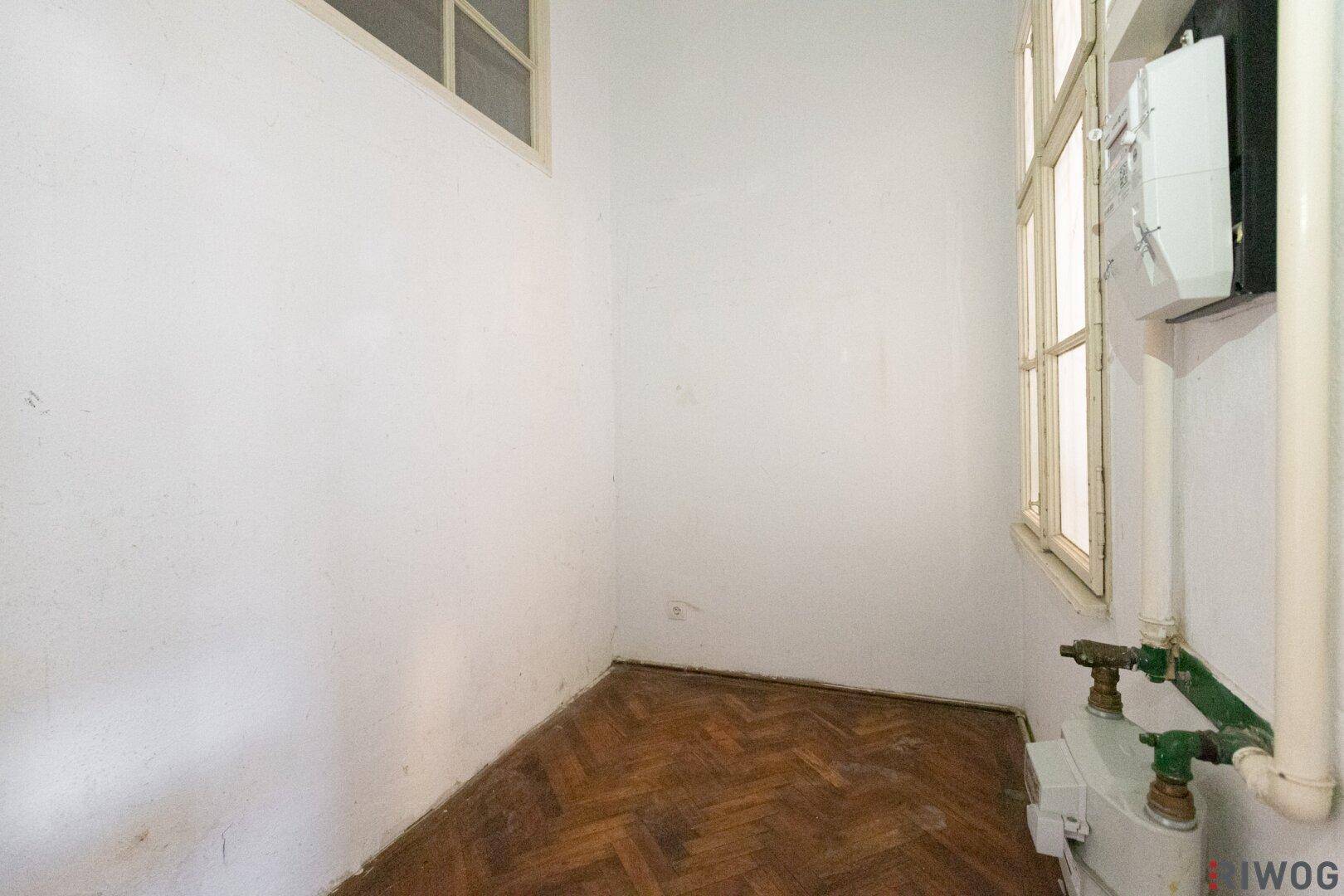 Kleiner Abstellraum mit Fenster, Gaszähler und sichtbaren Leitungen, ideal für Lagerzwecke.
