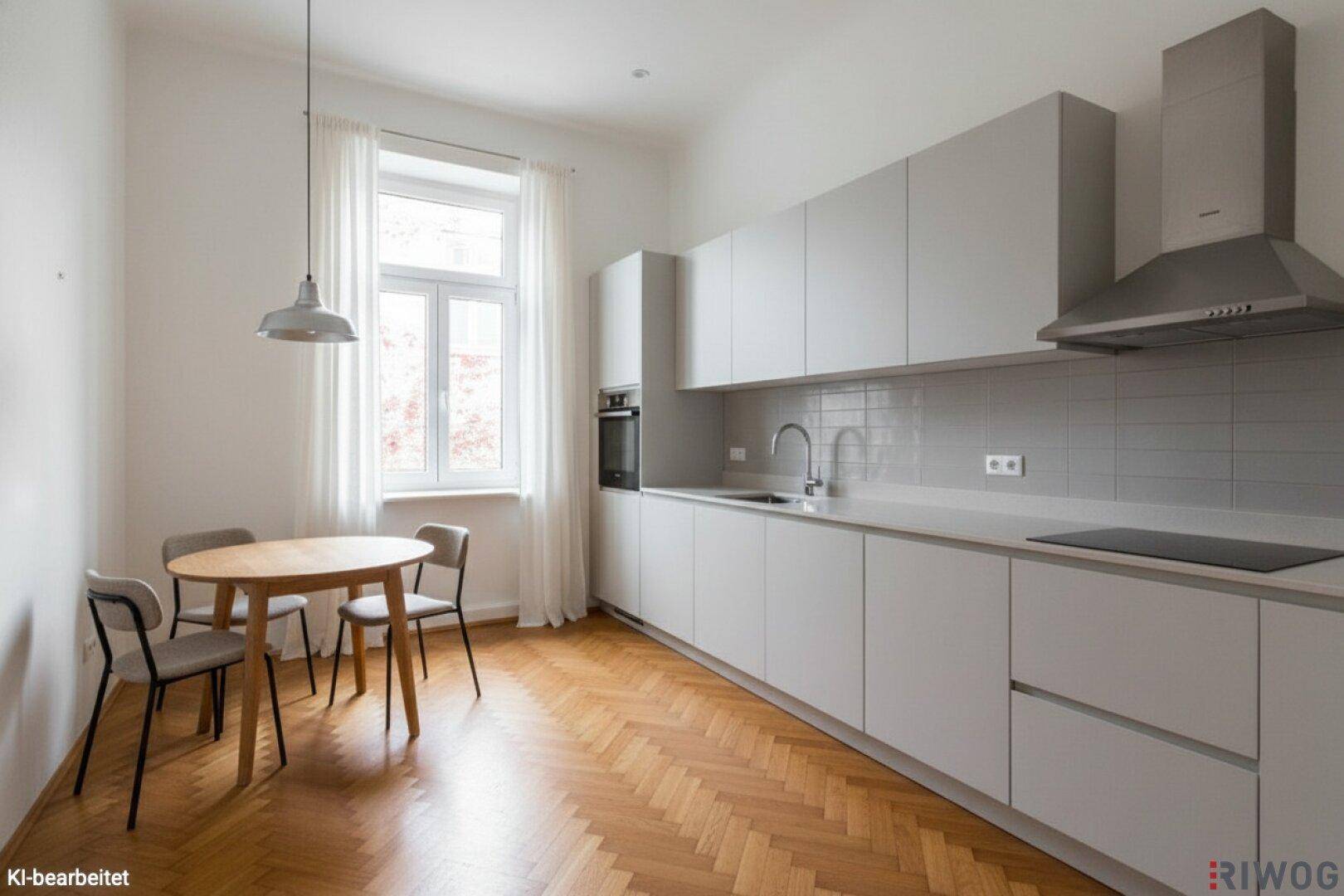 Moderne Einbauküche mit hellgrauen Schränken, Essbereich und Fischgrätparkett.