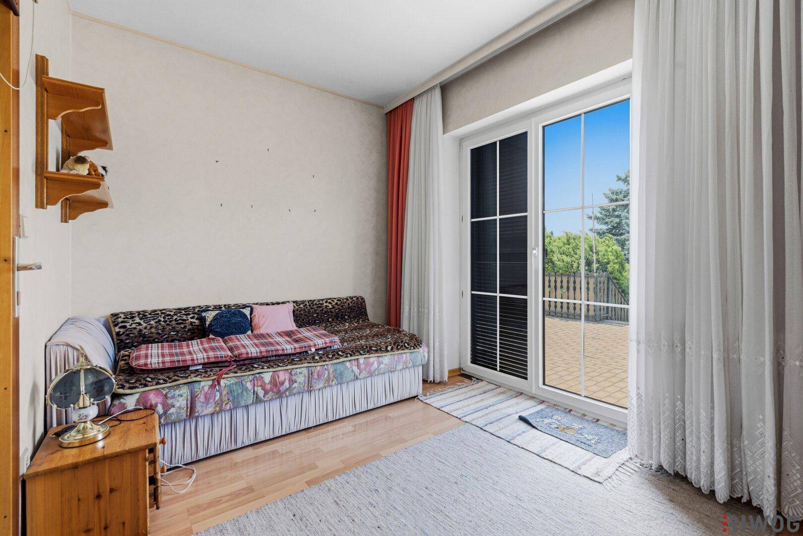 Weiterer Blick ins Schlafzimmer mit Tagesbett und der großen Fenstertür, die viel Licht hereinlässt.