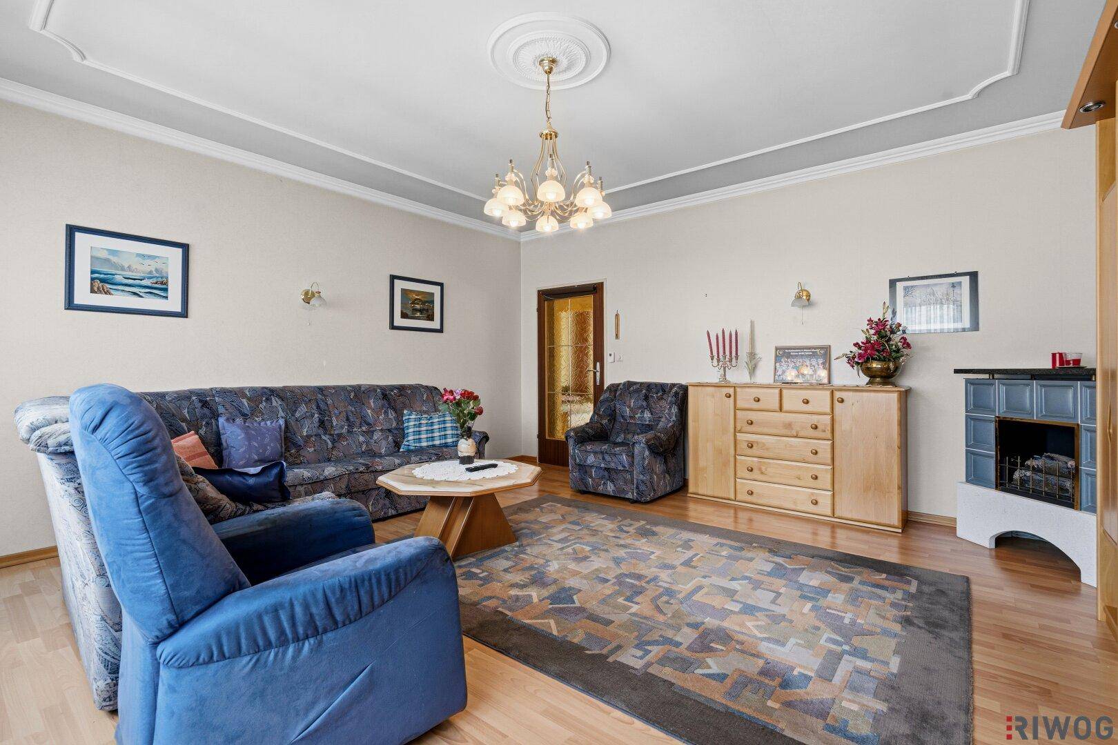 Weiterer Blick ins Wohnzimmer mit Kachelofen in der Ecke und gemütlicher Einrichtung.