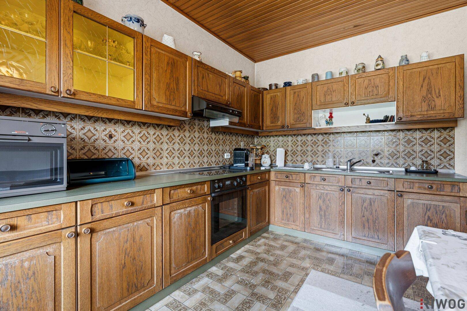 Detailansicht der Küche mit Einbaugeräten wie Backofen, Kochfeld und Dunstabzugshaube.