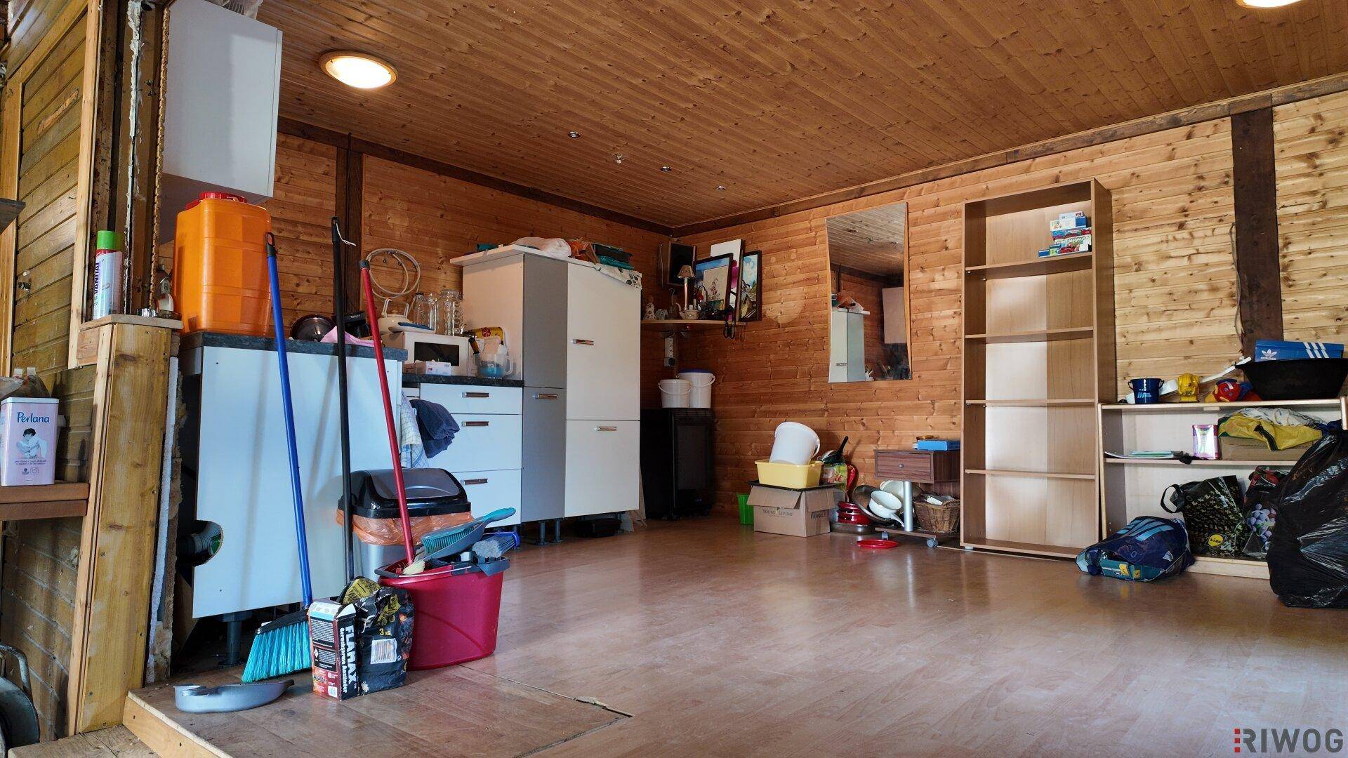 Geräumiger Abstellraum mit Holzwänden, Holzboden und verschiedenen Lagerregalen.