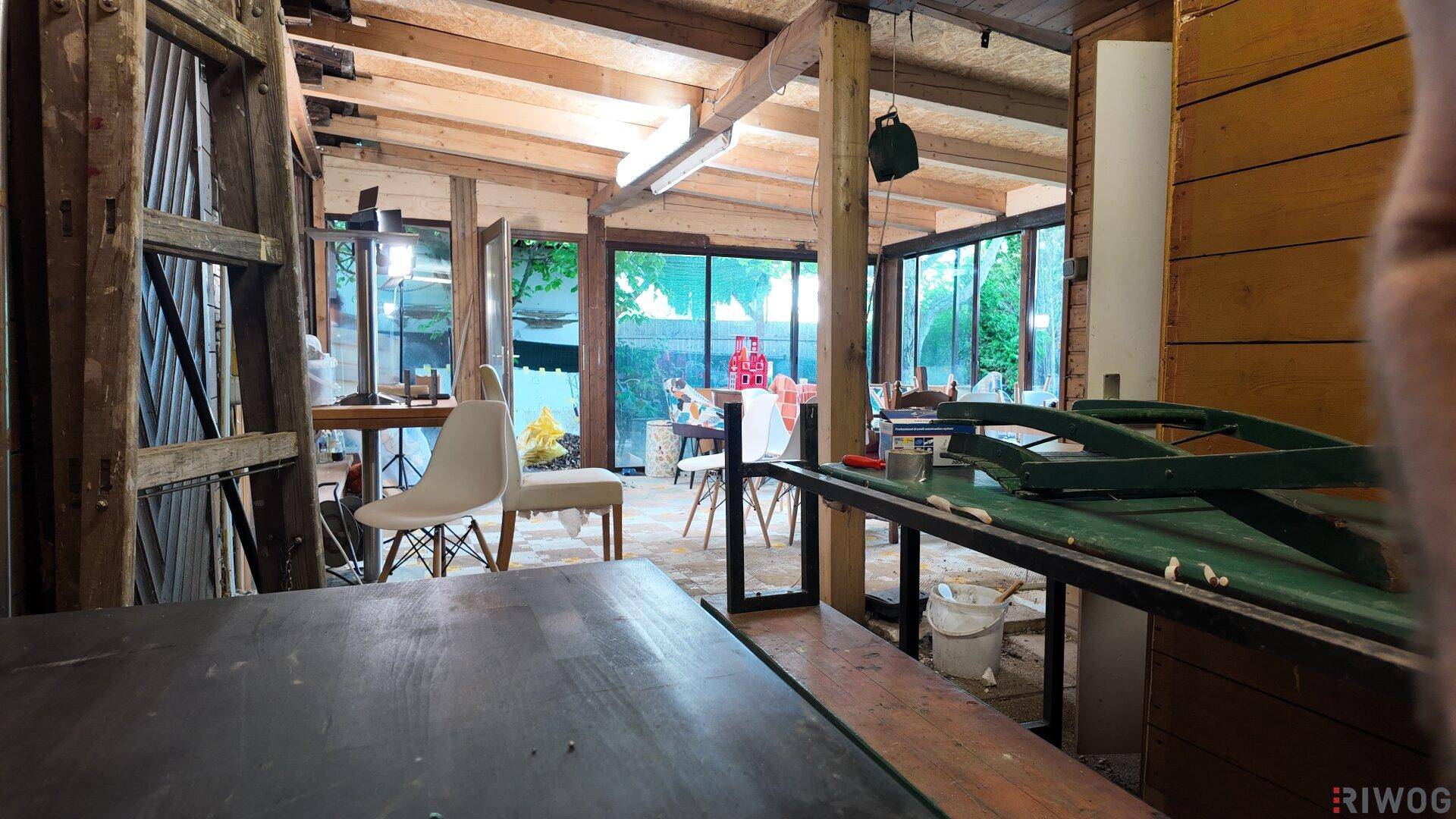 Innenraum mit sichtbaren Holzbalken und Blick in den angrenzenden Wintergarten.