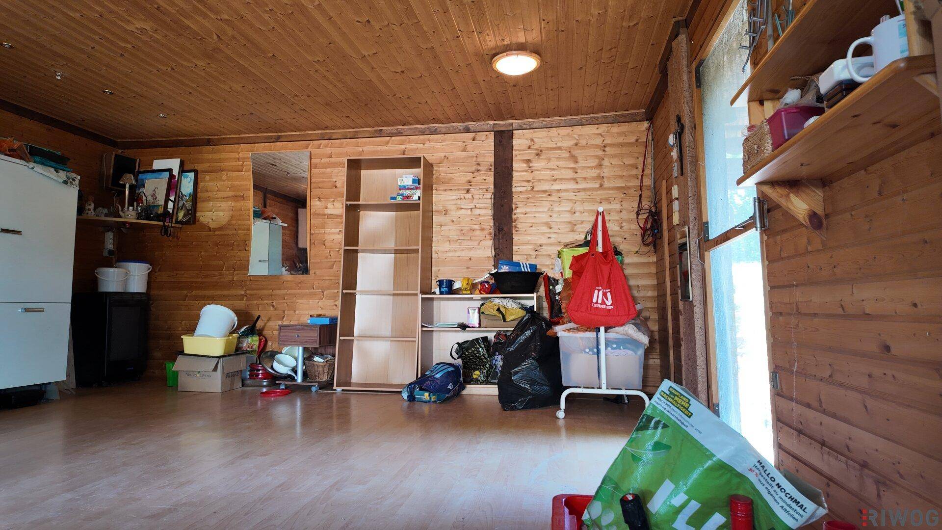 Innenraum mit Holzverkleidung, genutzt als Abstellraum mit Regalen und Gegenständen.