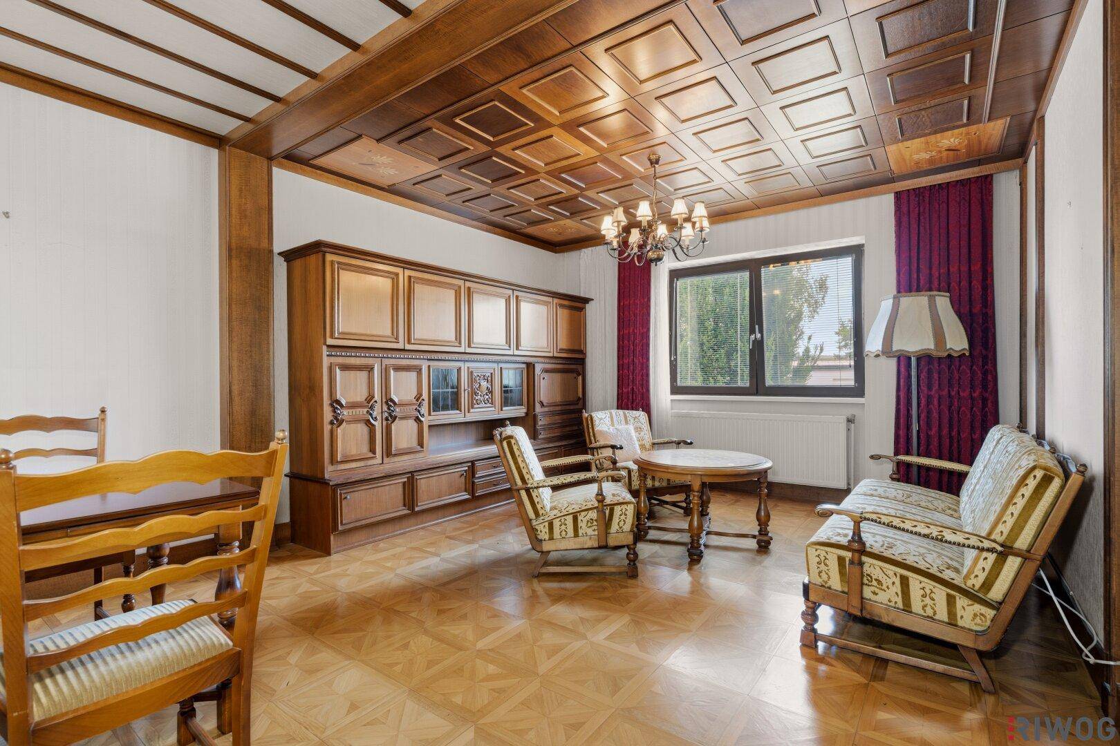 Traditionelles Wohnzimmer mit Holzkassettendecke, Parkettboden und klassischem Mobiliar.