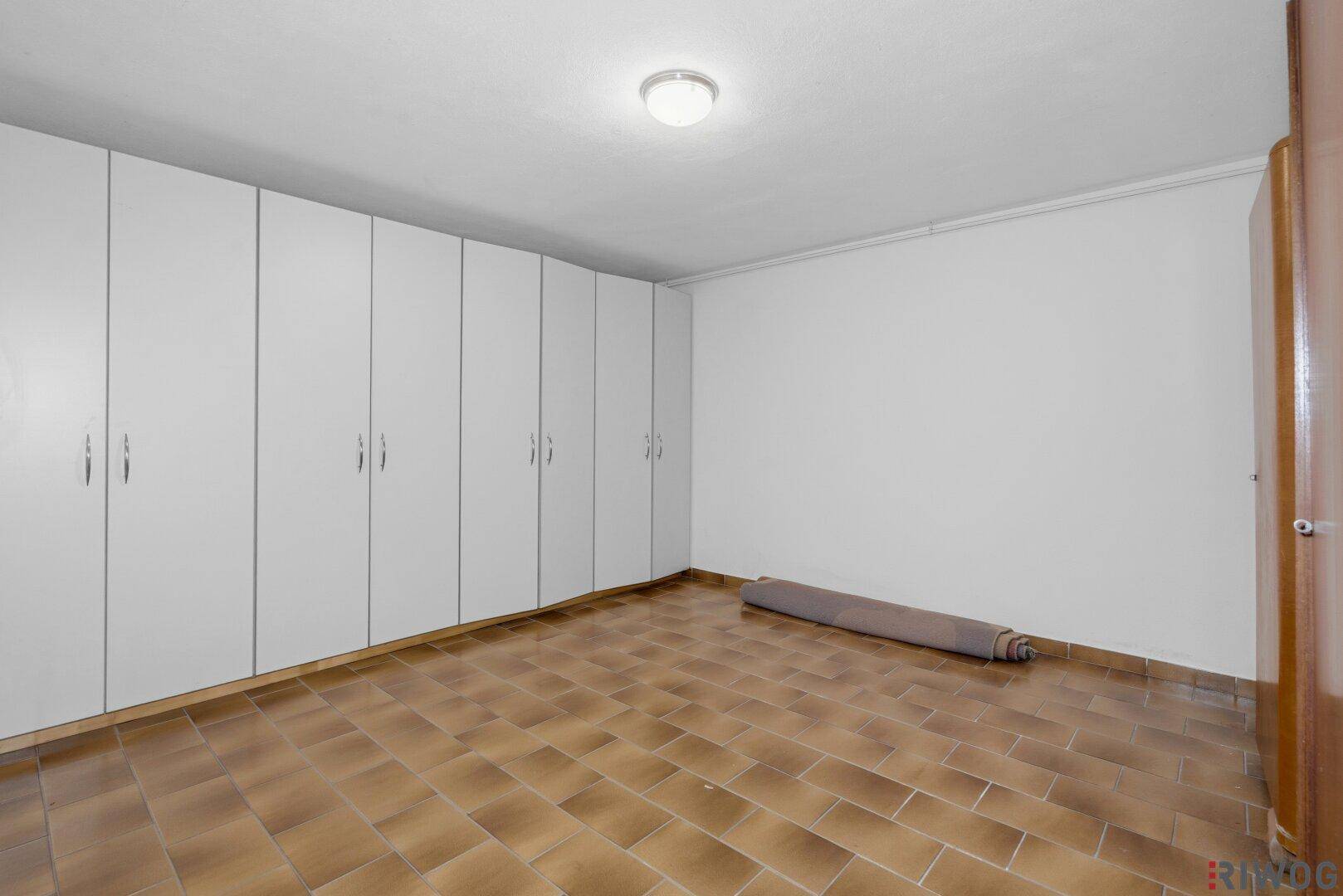 Geräumiger Kellerraum mit Einbauschränken und gefliestem Boden für zusätzlichen Stauraum.