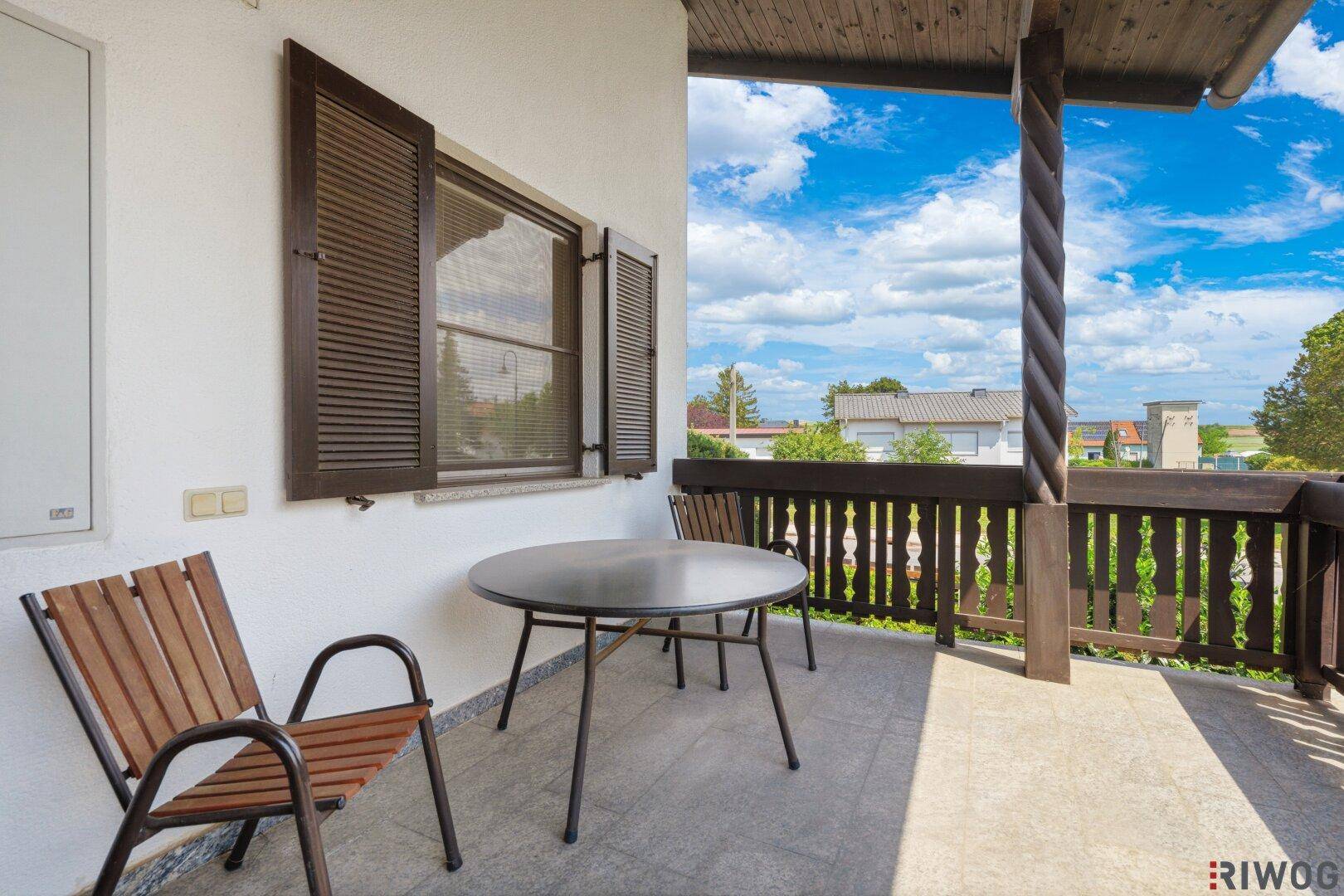 Gemütlicher Balkon mit Sitzgelegenheiten und Blick auf die Umgebung unter blauem Himmel.