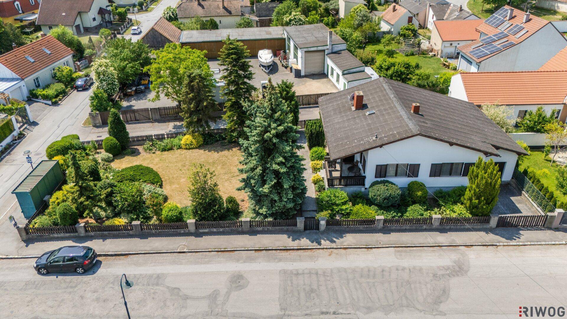 Luftaufnahme eines Einfamilienhauses mit weitläufigem Garten und angrenzenden Gebäuden.