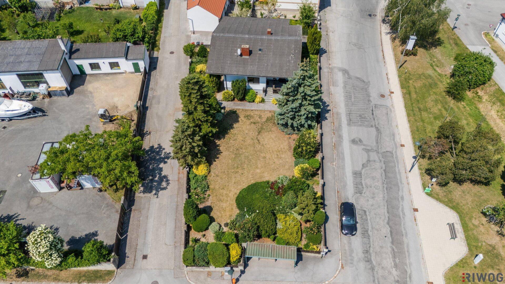 Weitläufige Luftaufnahme des Einfamilienhauses mit großem Garten und angrenzenden Straßen.