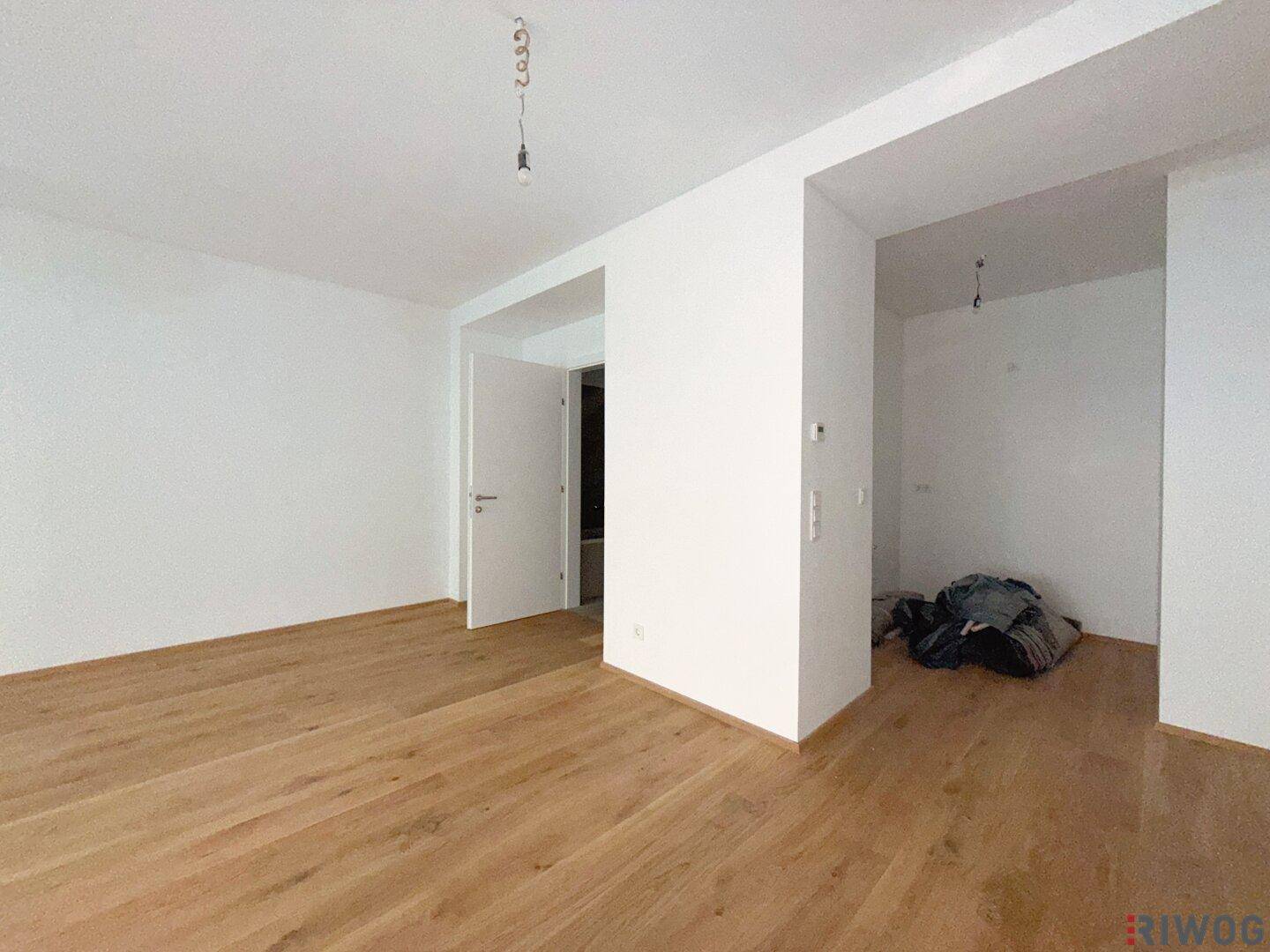 Leerer Raum mit neuem Holzfußboden und weißen Wänden, bereit für die individuelle Gestaltung.