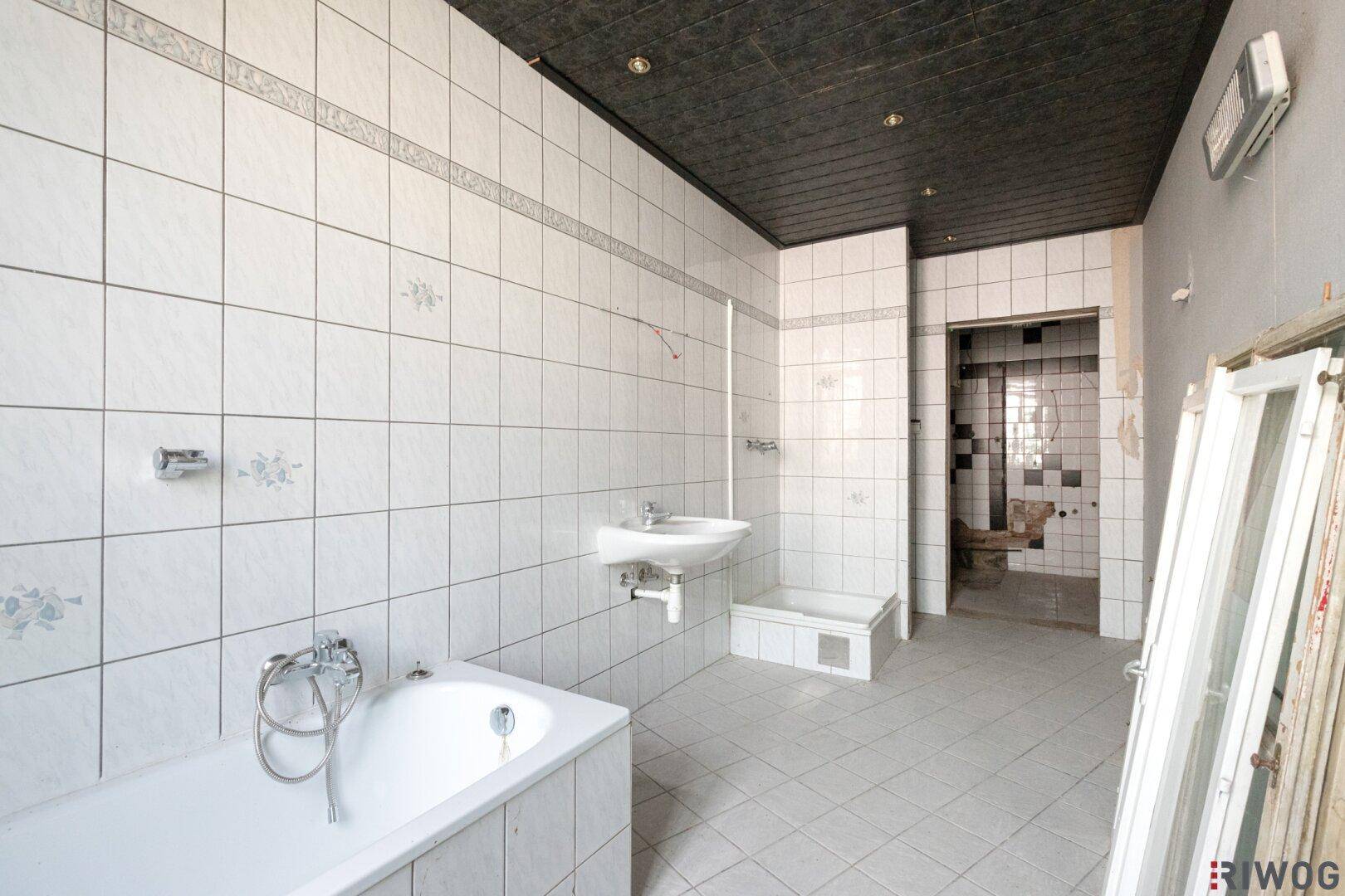 Badezimmer mit Badewanne, Waschbecken und Fliesen, das eine umfassende Renovierung benötigt.