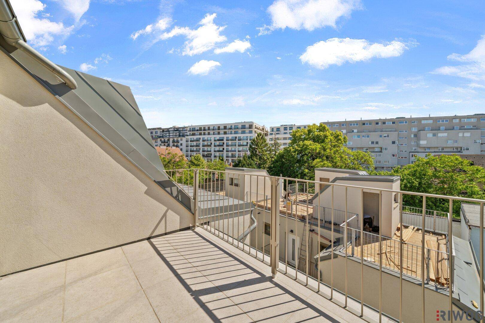 Großer Balkon mit Fliesenboden und weitem Blick über die Stadt und Grünflächen.