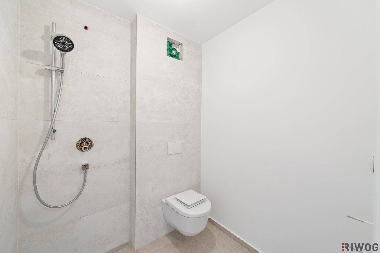 Modernes Badezimmer mit bodengleicher Dusche und wandhängendem WC, hell gefliest.