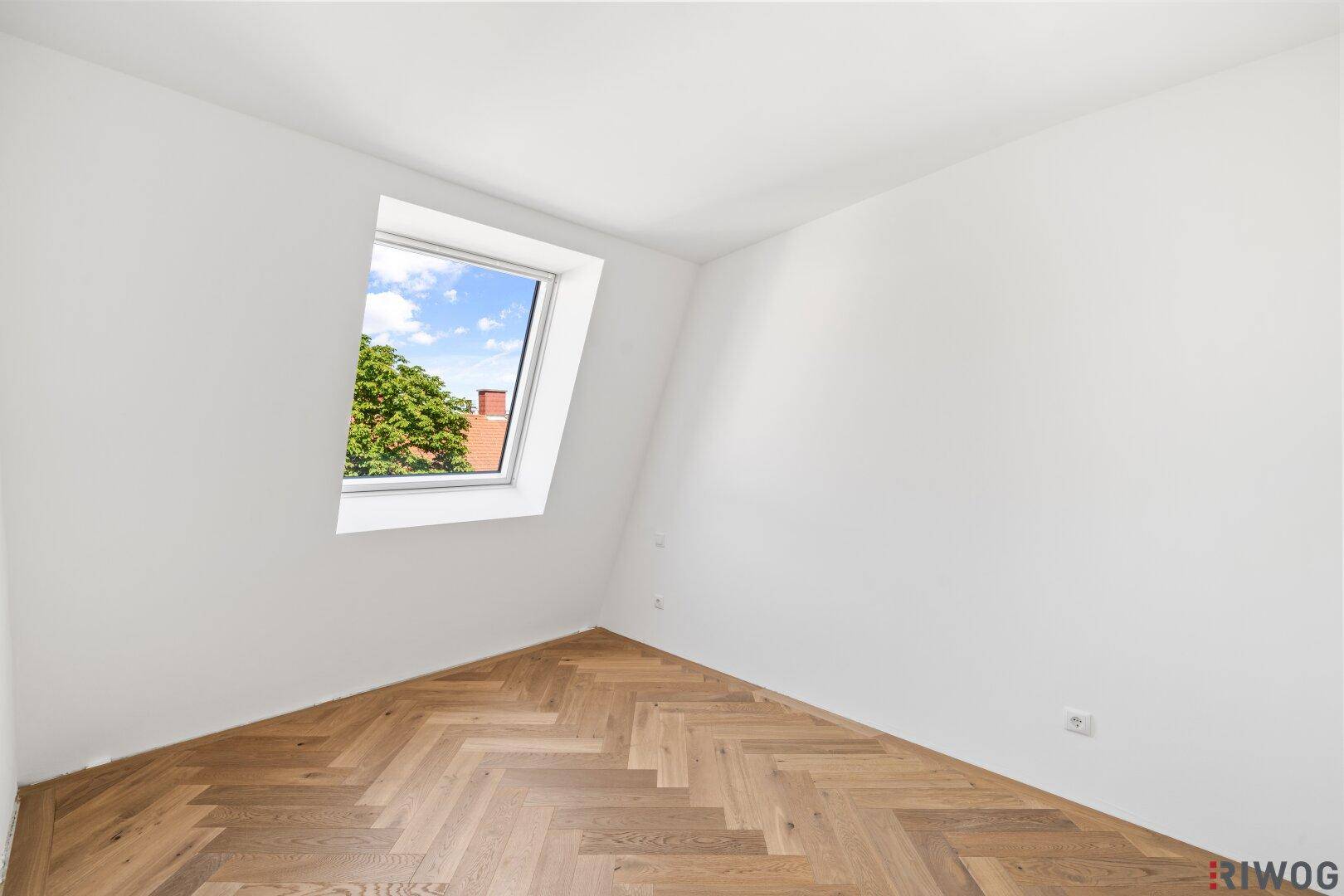 Helles Zimmer mit Fischgrätparkett und Dachschräge, ideal als Kinder- oder Arbeitszimmer.